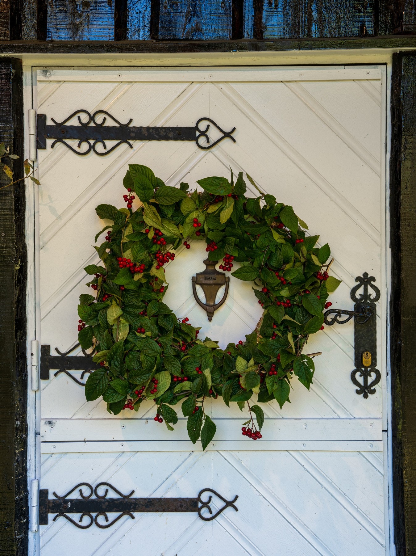 Den klassiske hvite hyttedøren med smijernsbeslag og dekorativ krans ønsker deg velkommen. Galleribilde