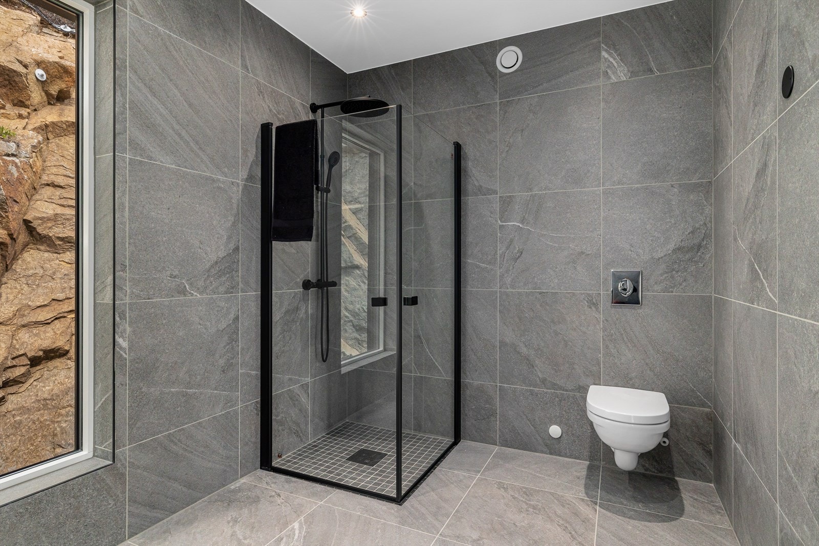 Badet har vegghengt toalett, servant på en romslig skuffeinnredning med overhengende speil samt dusjhjørne. Galleribilde
