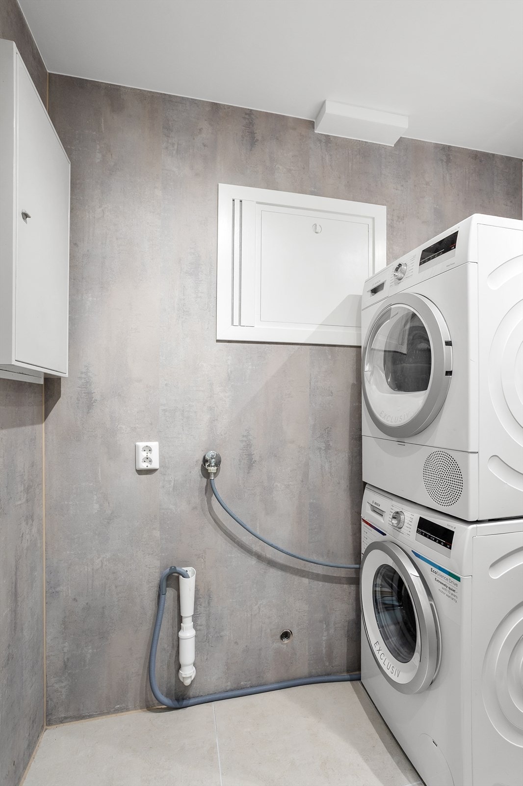 Eget vaskerom med moderne flater og opplegg for vaskesøyle. Galleribilde