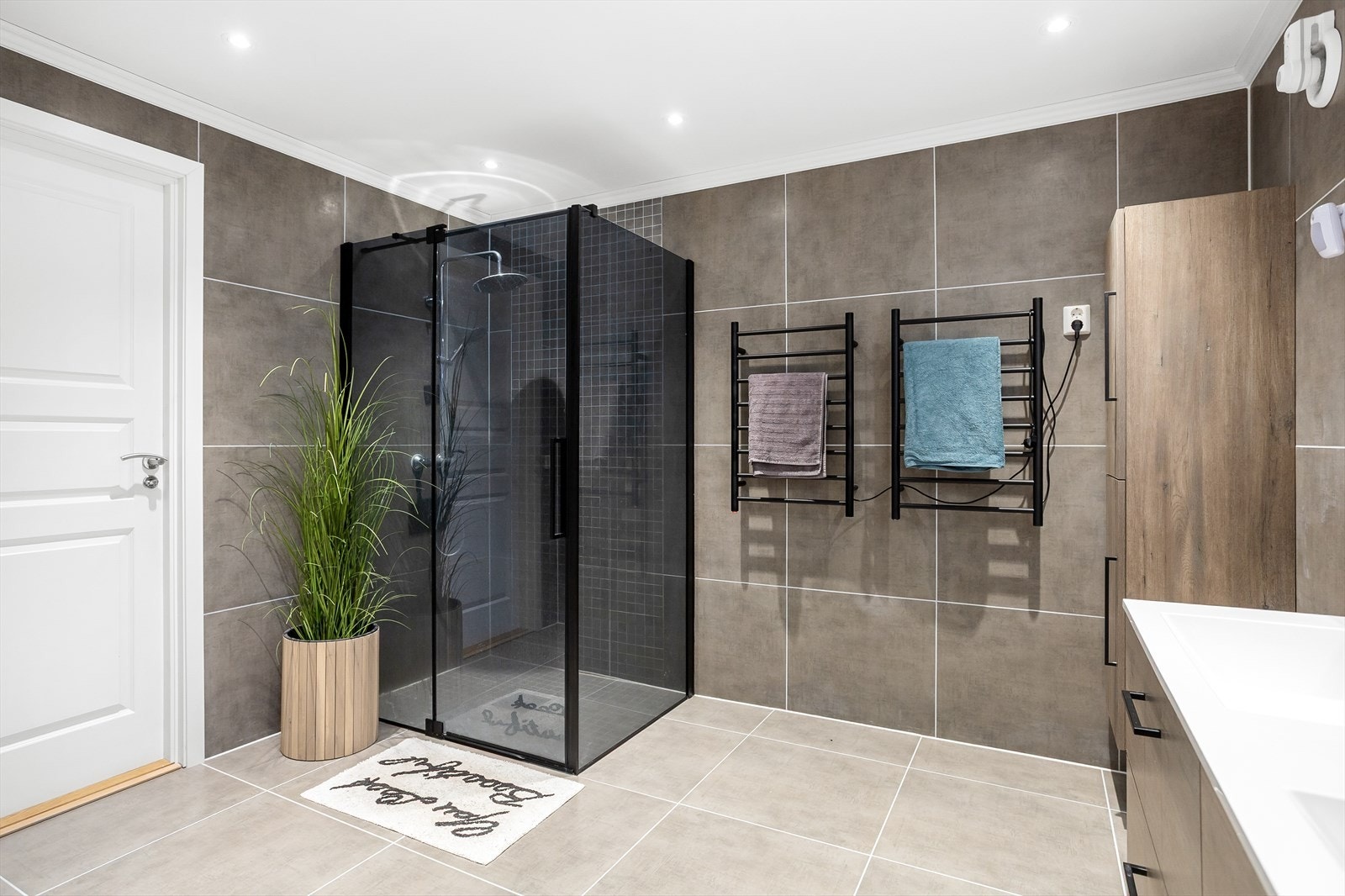 Elegant, flislagt bad med regnfallsdusj og lekre, sorte detaljer. Galleribilde