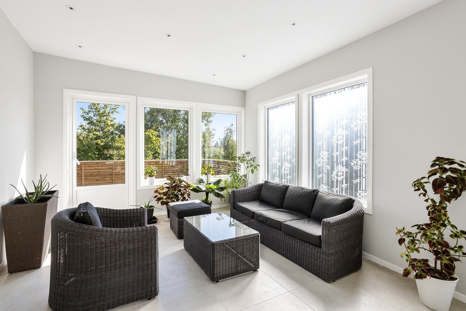 Store vindusflater og flislagt gulv. Utgang til usjenerte, grønne omgivelser. Galleribilde