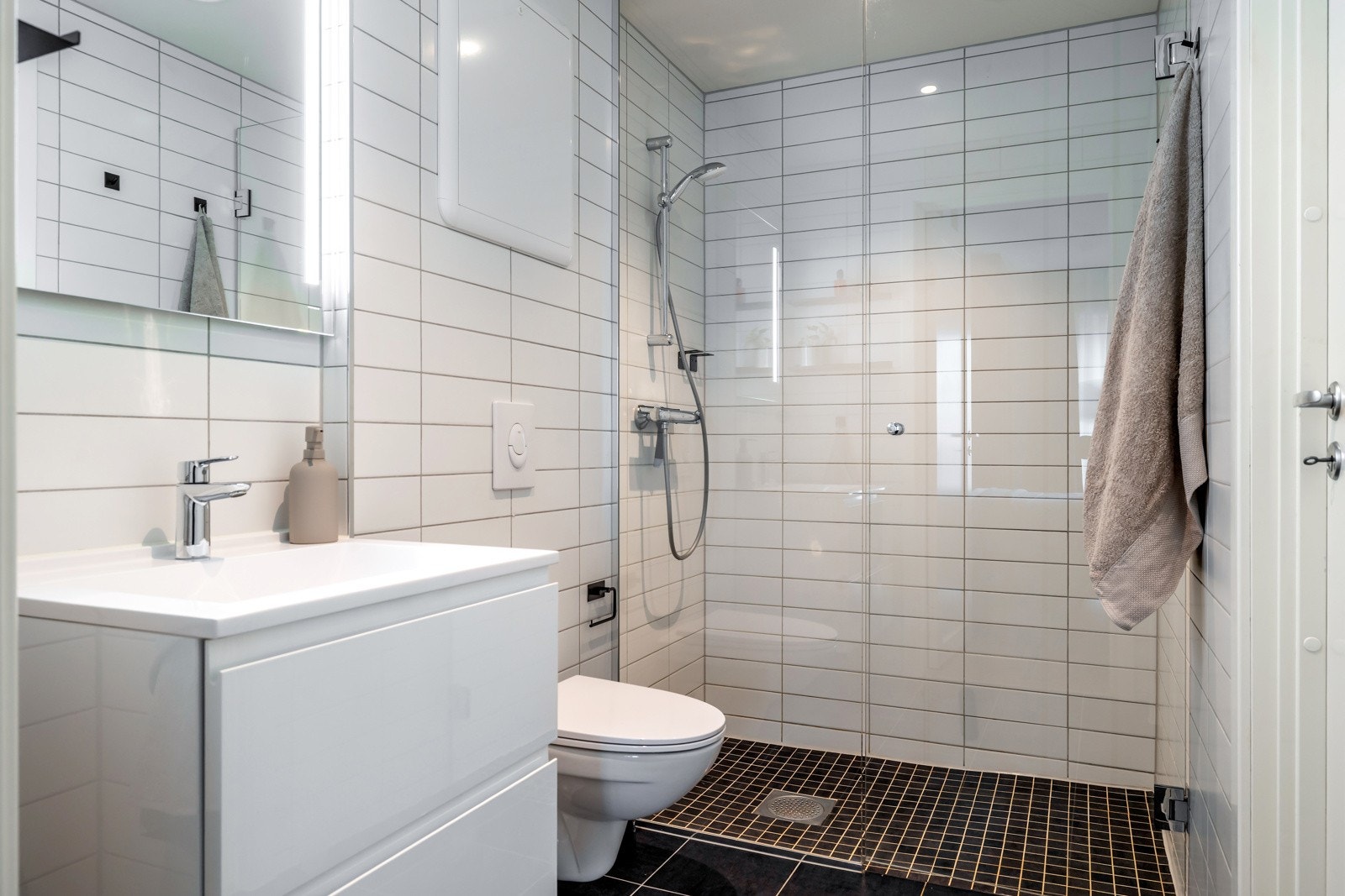 Badet er flislagt med gulvvarme og har downlights med dimmer Galleribilde