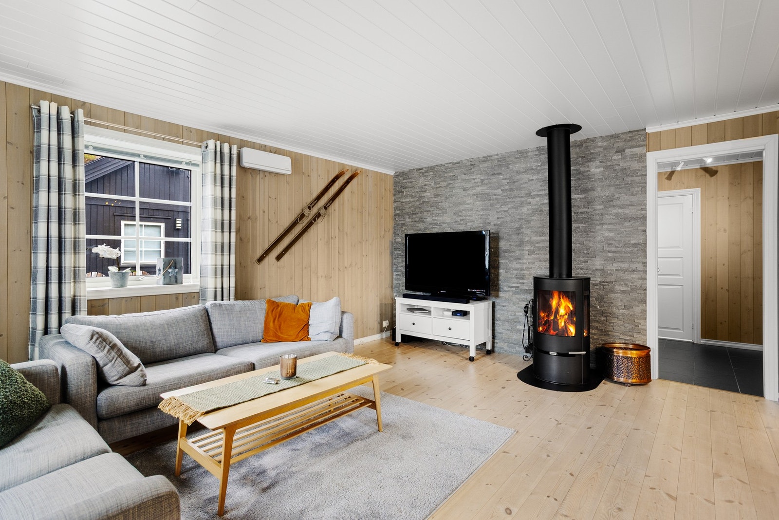 Nydelig stue med lune panelvegger, tregulv og steinsatt brannmur Galleribilde