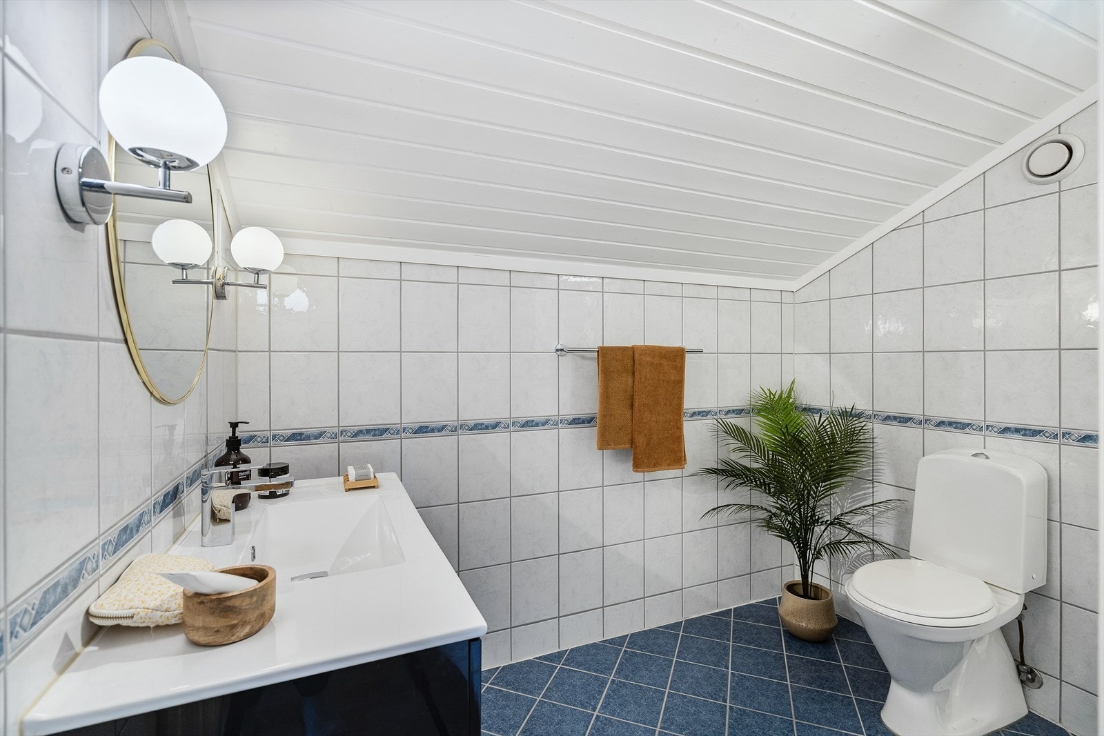 Badet i andre etasje har blå gulvfliser med varme og hvite veggfliser med noe dekor Galleribilde