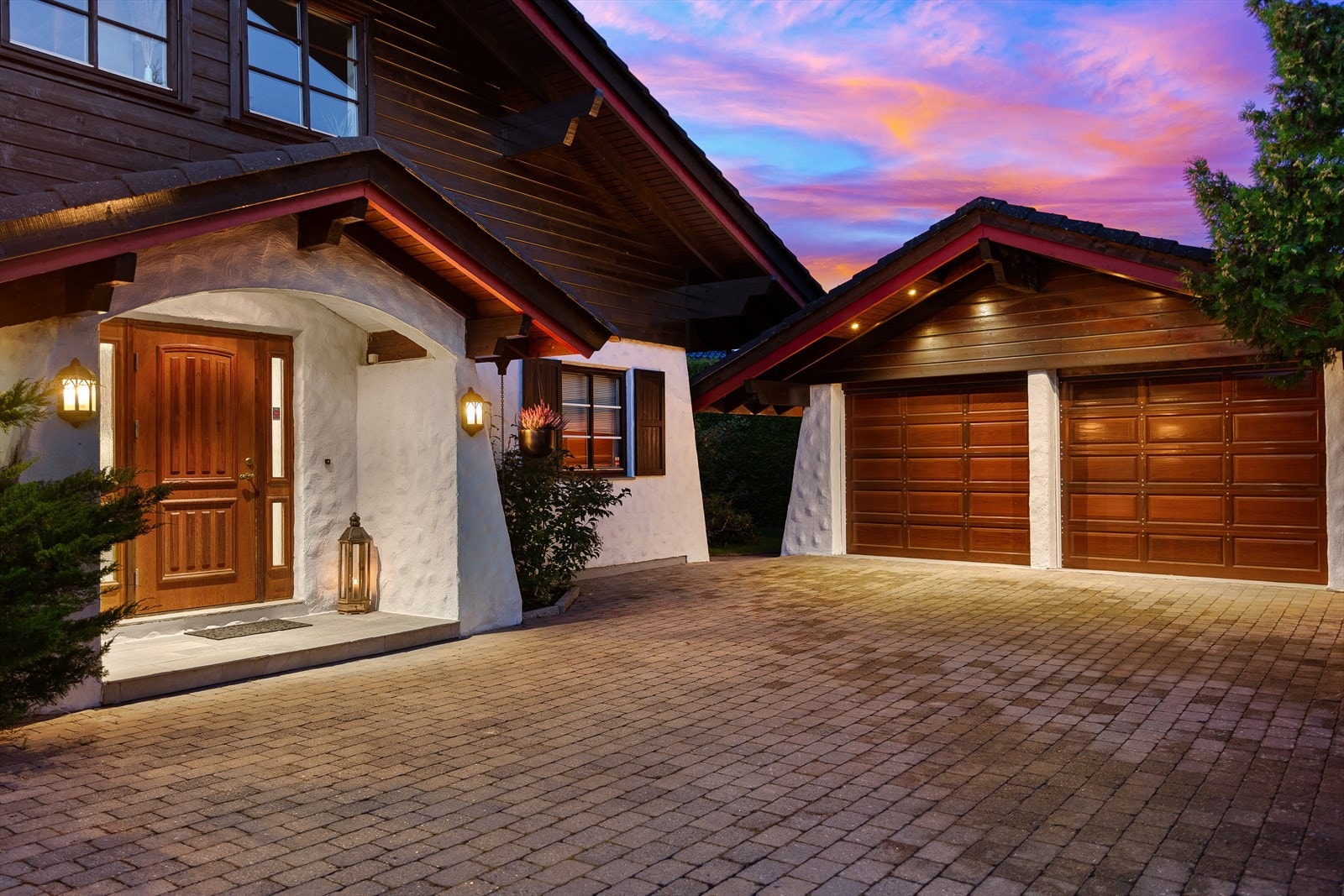 Pent opparbeidet innkjørsel med beleggningstein, dobbelgarasje med el-lader, trær og beplantning Galleribilde