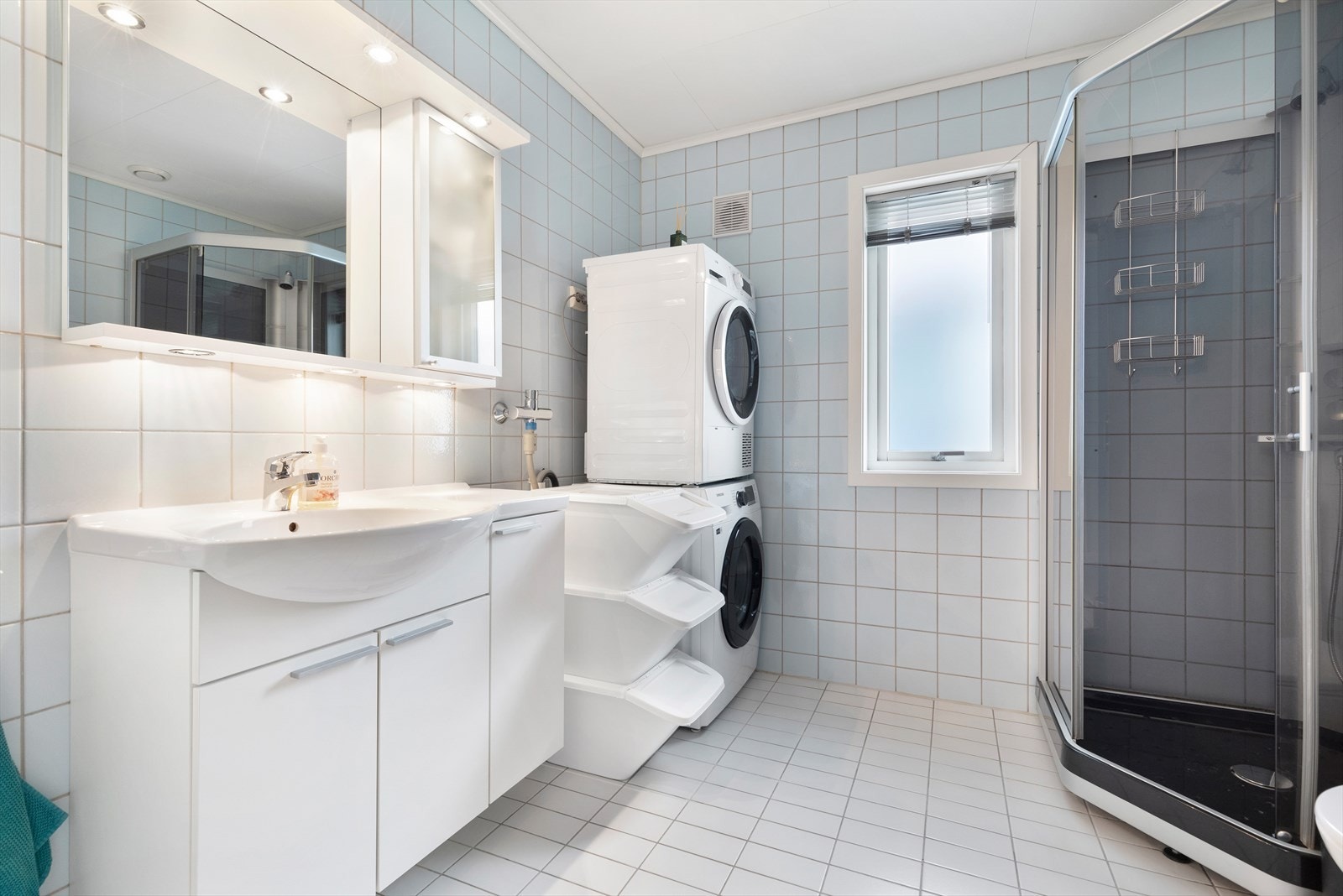 Bad med malte takplater, fliser på vegger og gulv, innredning med wc og dusjkabinett, samt opplegg for vaskemaskin og stikkontakt til tørketrommel. Galleribilde