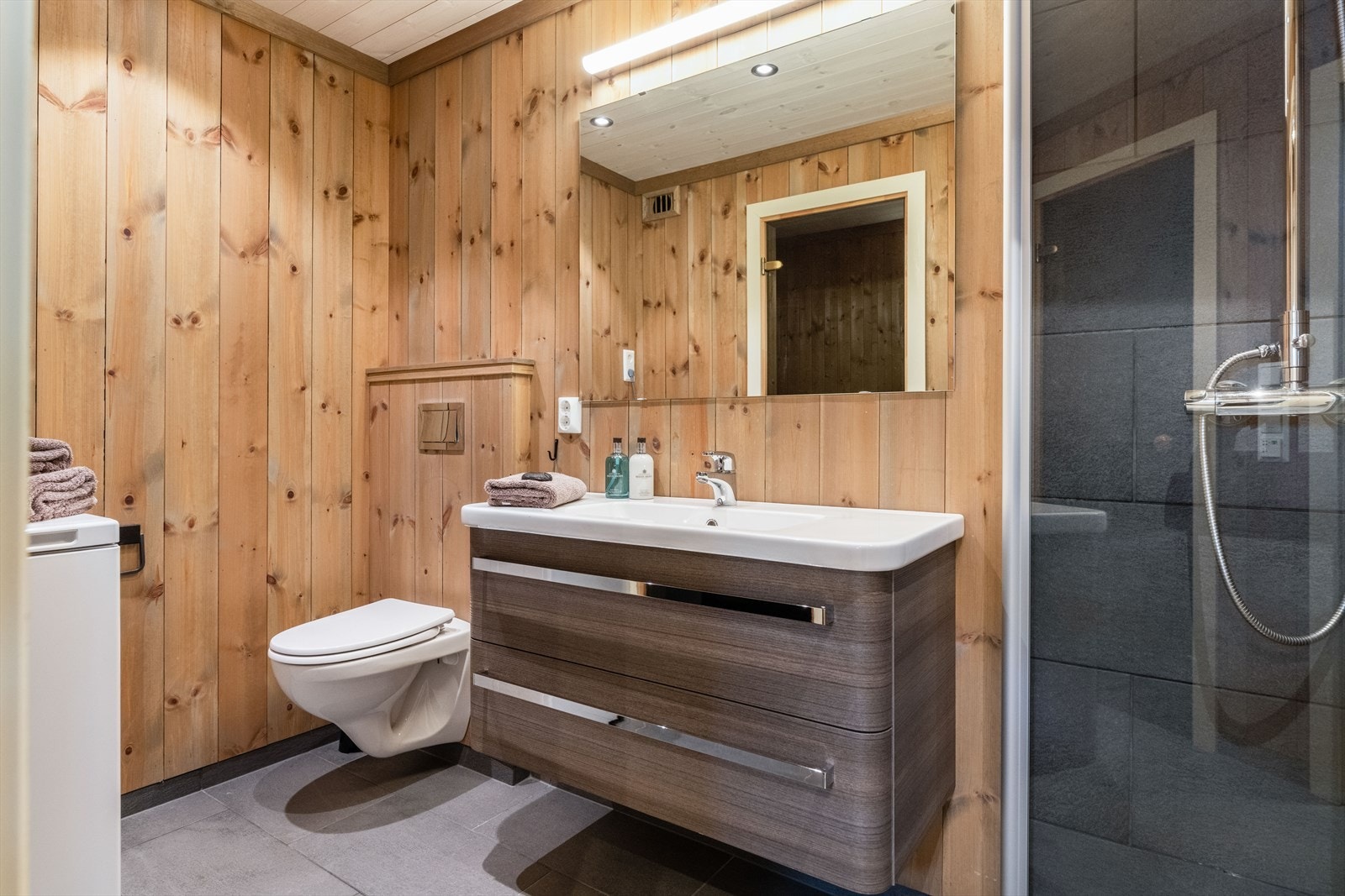 Fritidsboligens andre bad har ligger med inngang fra hallen. Her er det flis på gulv og i dusjhjørne, ellers panel på vegger. Galleribilde