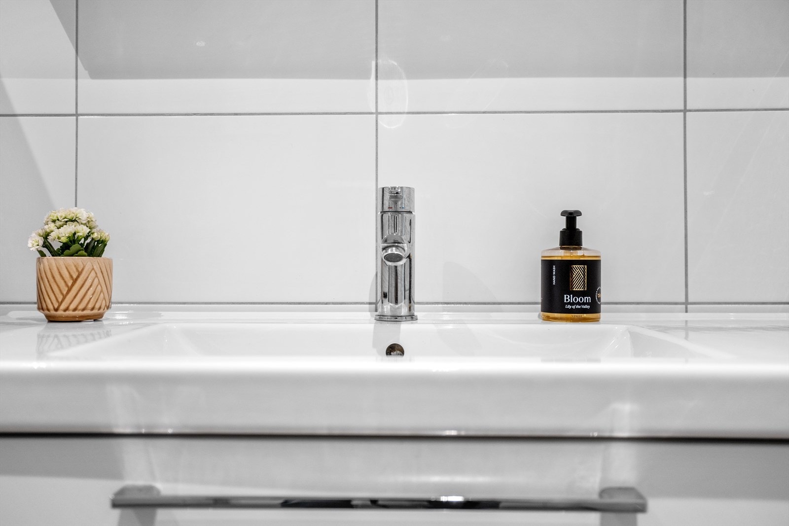 Veggene har tidsriktige, rektangulære veggfliser mens det på gulvet er valgt en gråtonet og lun farge for å skape en matchende og moderne kontrast. Galleribilde