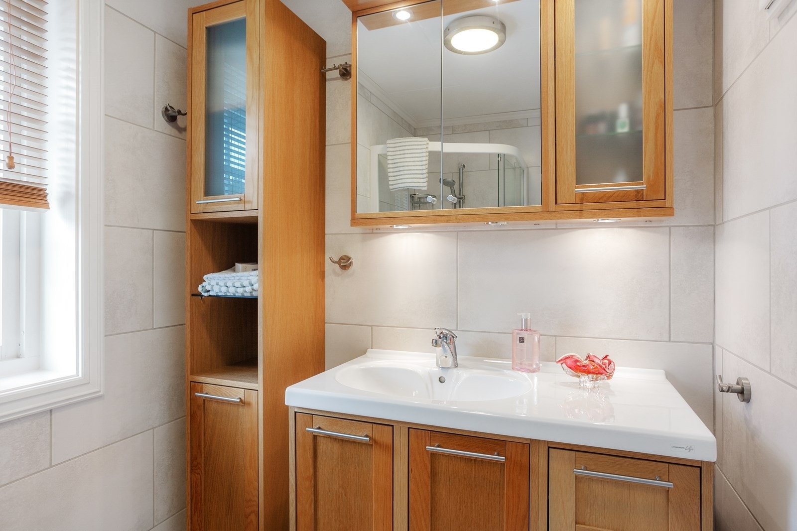 Badet er innredet med nedfelt servant, veggmontert toalett og dusjhjørne. Galleribilde