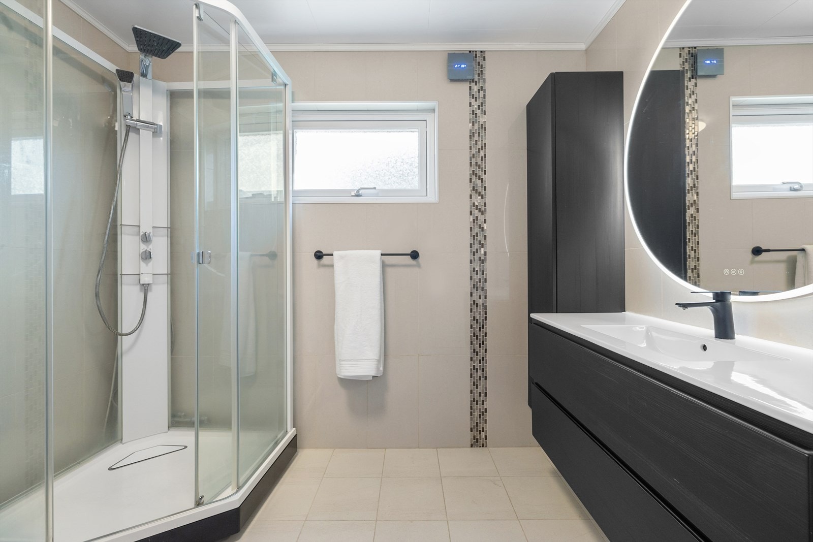 Badet ble renovert i 2020, helfliset i lune farger med tøff, sort innredning. Galleribilde