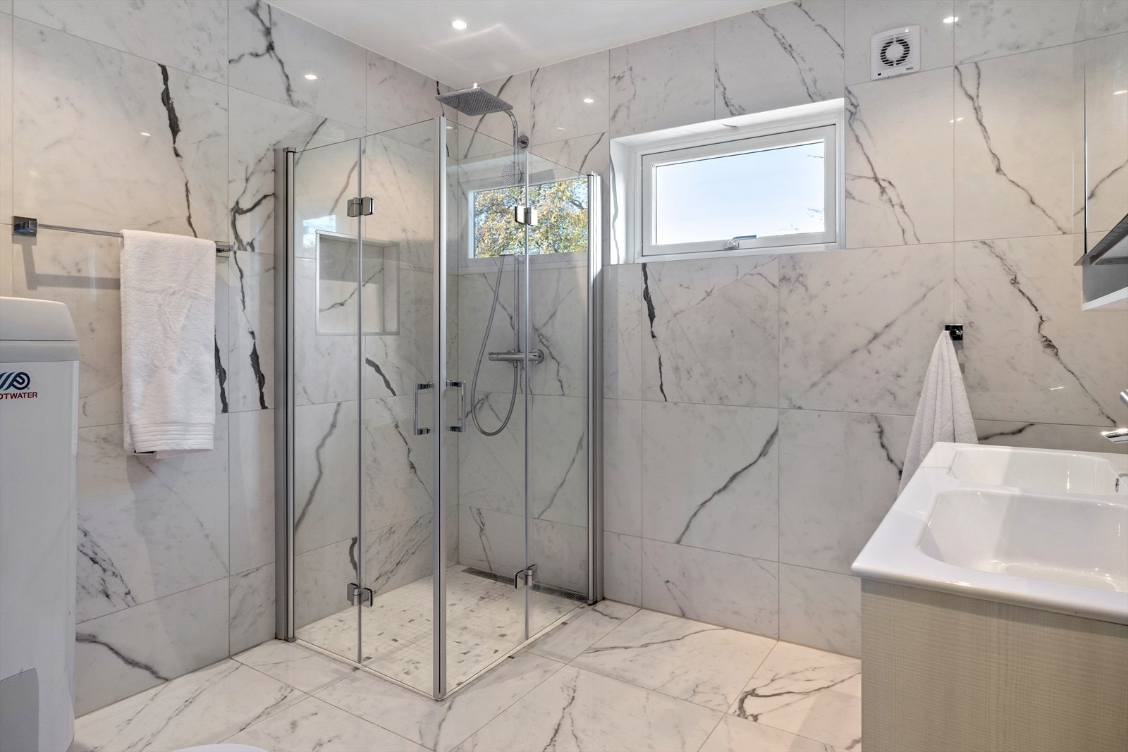 Dette badet har marmorerte fliser, dusjvegger og innredning med dobbel servant. Galleribilde