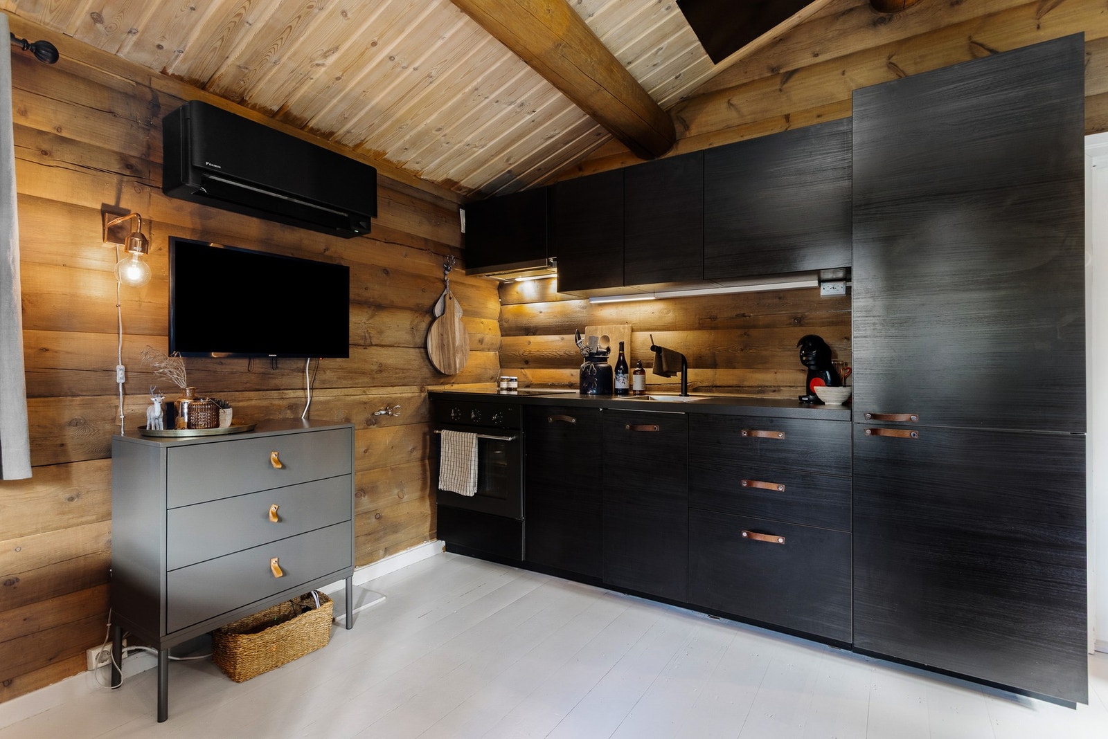 Nyere kjøkkeninnredning med lekre, sorte fronter og overskap. Kjøkkenet inneholder komfyr med koketopp, oppvaskmaskin, kjøleskap og ventilator Galleribilde