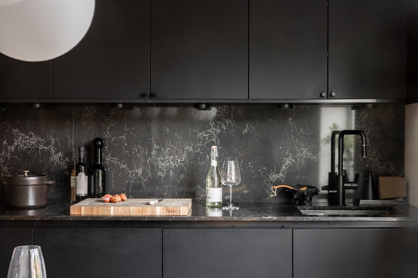 Kvalitetskjøkken fra HTH med svarte fronter, komposittstein som benkeplate og veggpanel Galleribilde