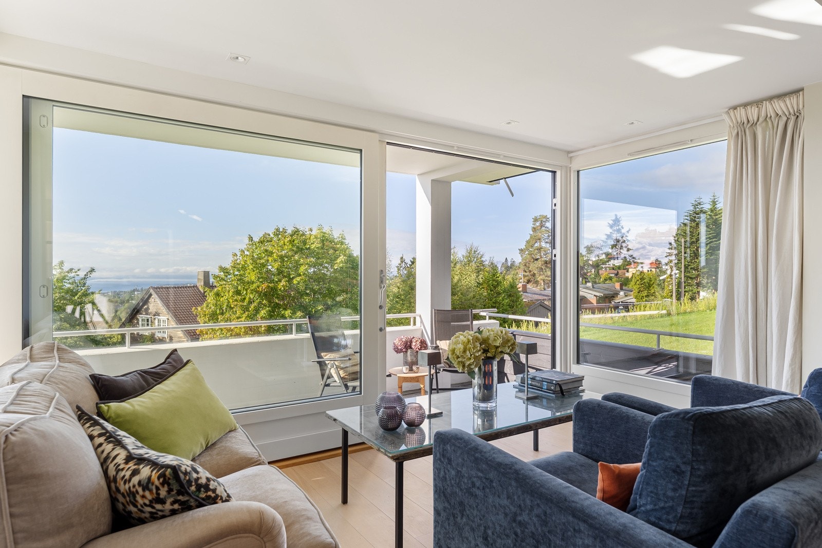 Stue med store vindusflater og plass til flere hyggelig sittegrupper Galleribilde