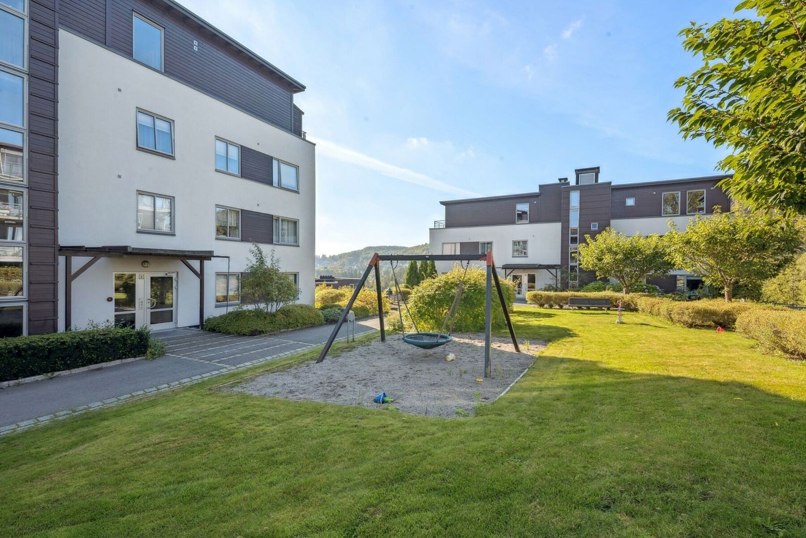 Inngangspartiet og tunet, som er parkmessig opparbeidet og har flere sitteplasser med bord og benker. Galleribilde