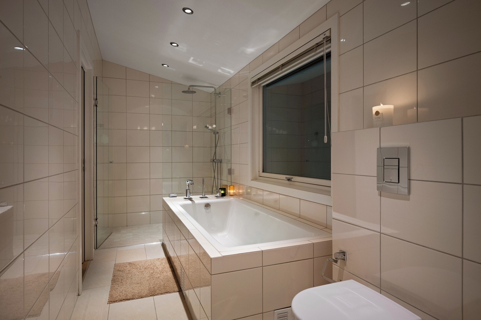 Badet har innredning med nedfelt servant, veggmontert toalett, badekar og dusjvegger/hjørne Galleribilde