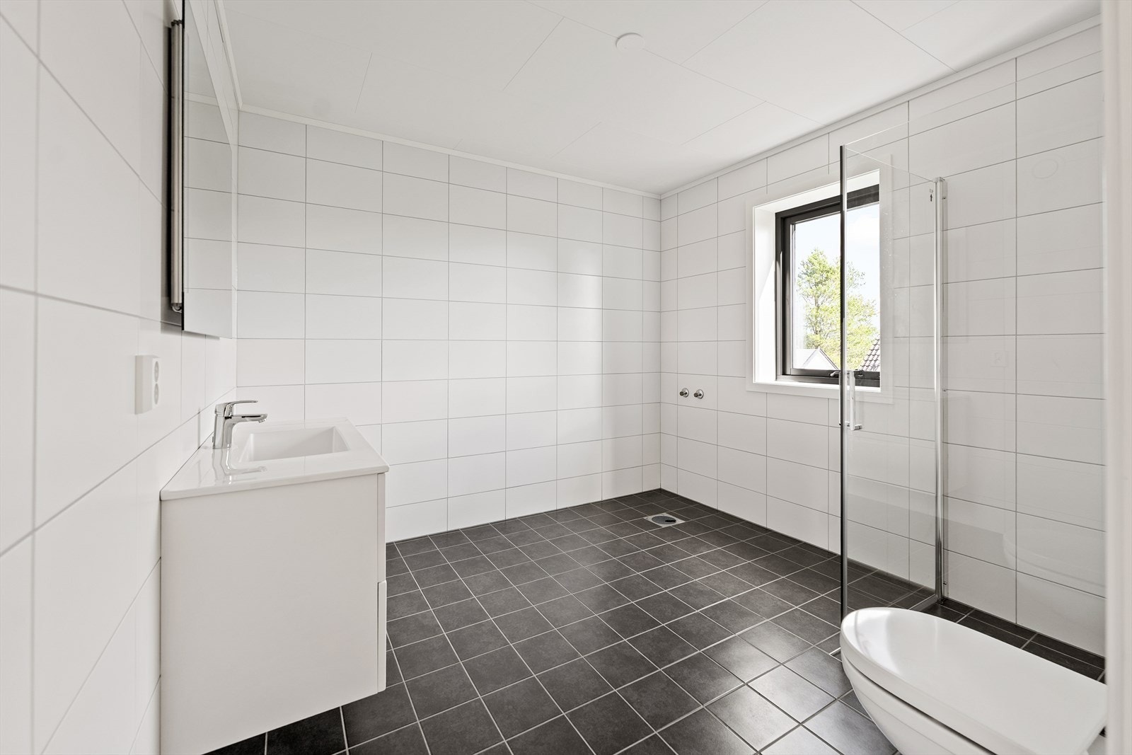 Boligen har et moderne bad i andre etasje, med stilrene materialvalg og god plass til både dusj og oppbevaring. Galleribilde