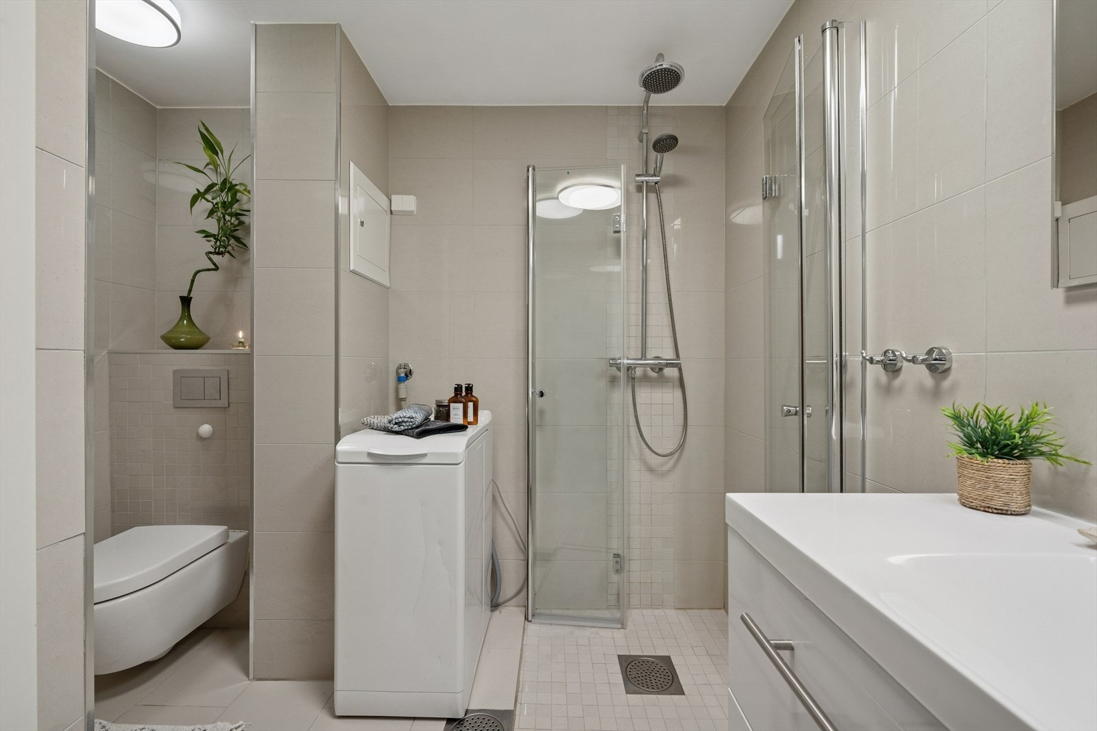 Videre er det veggmontert toalett, dusjvegger/hjørne og opplegg for vaskemaskin. Galleribilde