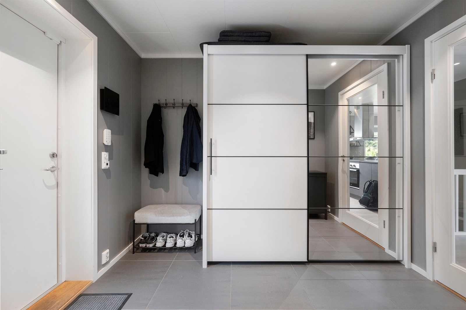 Romslig og lys entré med flislagt gulv og skyvedørsgarderobe. Galleribilde