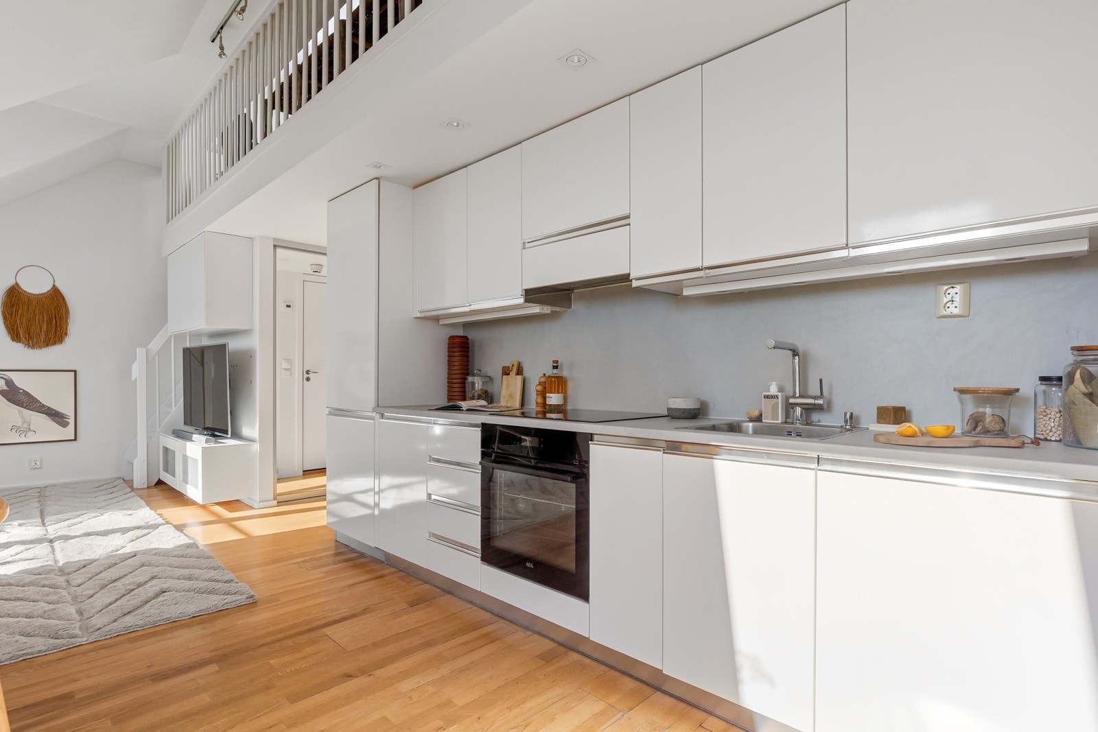 Kjøkkenet har benke- og overskap med slette fronter, benkeplate av laminat og kitchenboard på vegg over benk Galleribilde