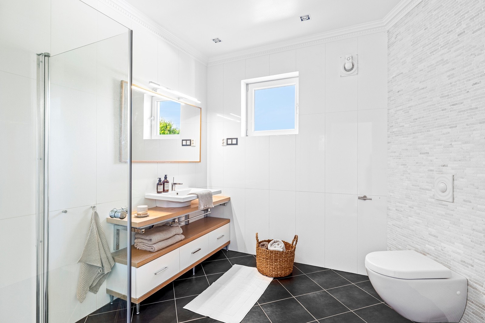 Badet i første etasje ligger i hendig tilknytning til hallen, og har hvite og lysegrå fliser på veggene og koksgrå fliser på gulv med vannbåren gulvvarme. Galleribilde