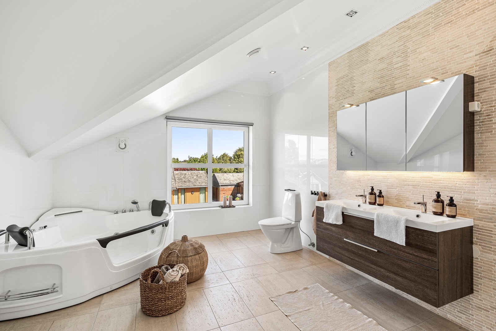 Her er det en kombinasjon av hvite- og sandfargede veggfliser, og på gulvet er det matchende fliser og vannbåren gulvvarme. Galleribilde