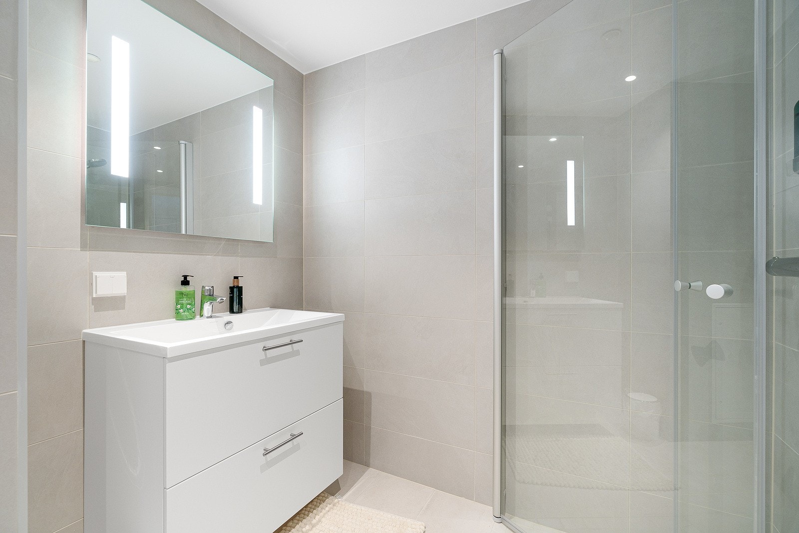 Lys baderomsinnredning og speil med innebygget belysning. Galleribilde