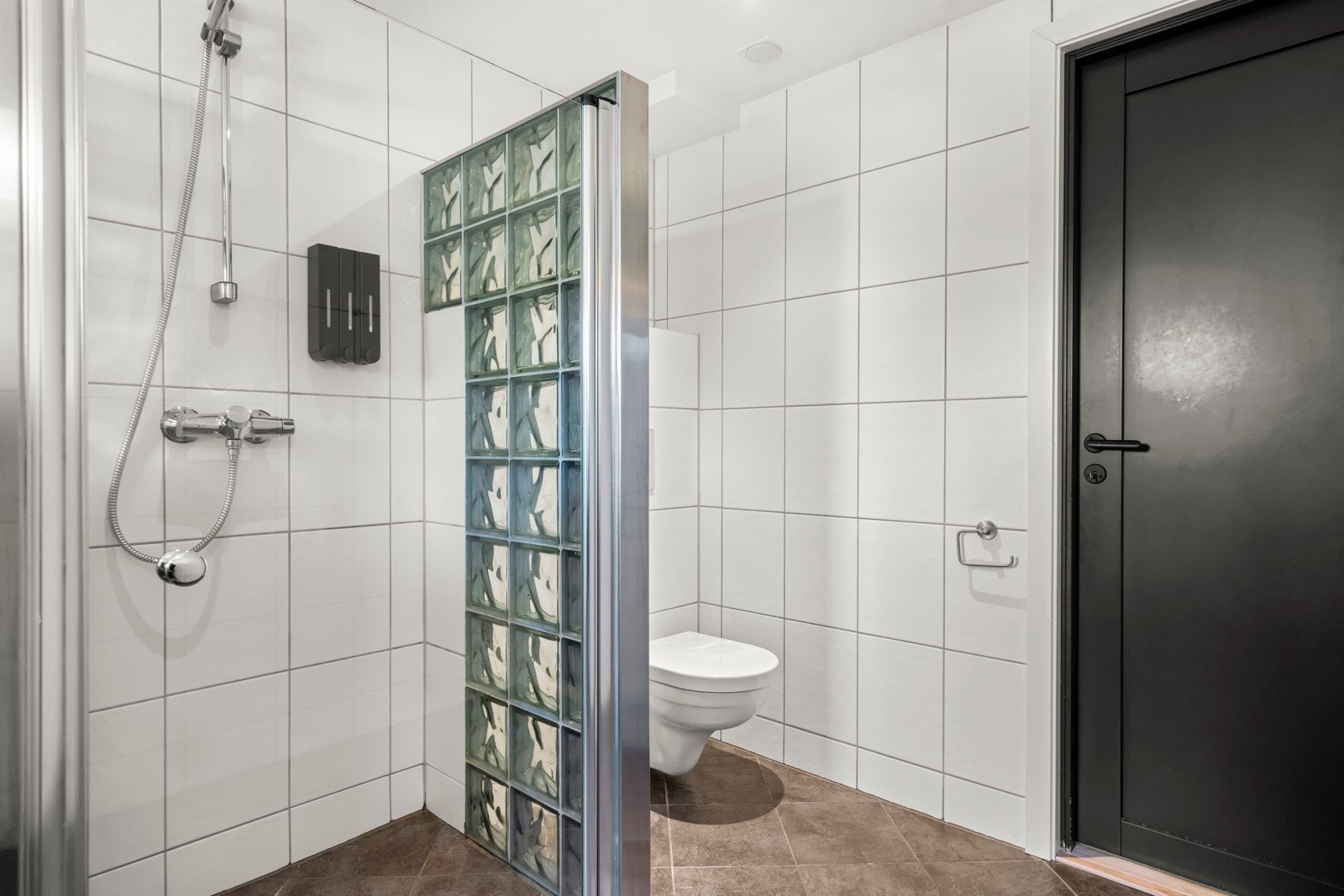 Dusjsone med svingdør i glass i tillegg finner du veggmontert klosett som gir et moderne og praktisk preg. Galleribilde