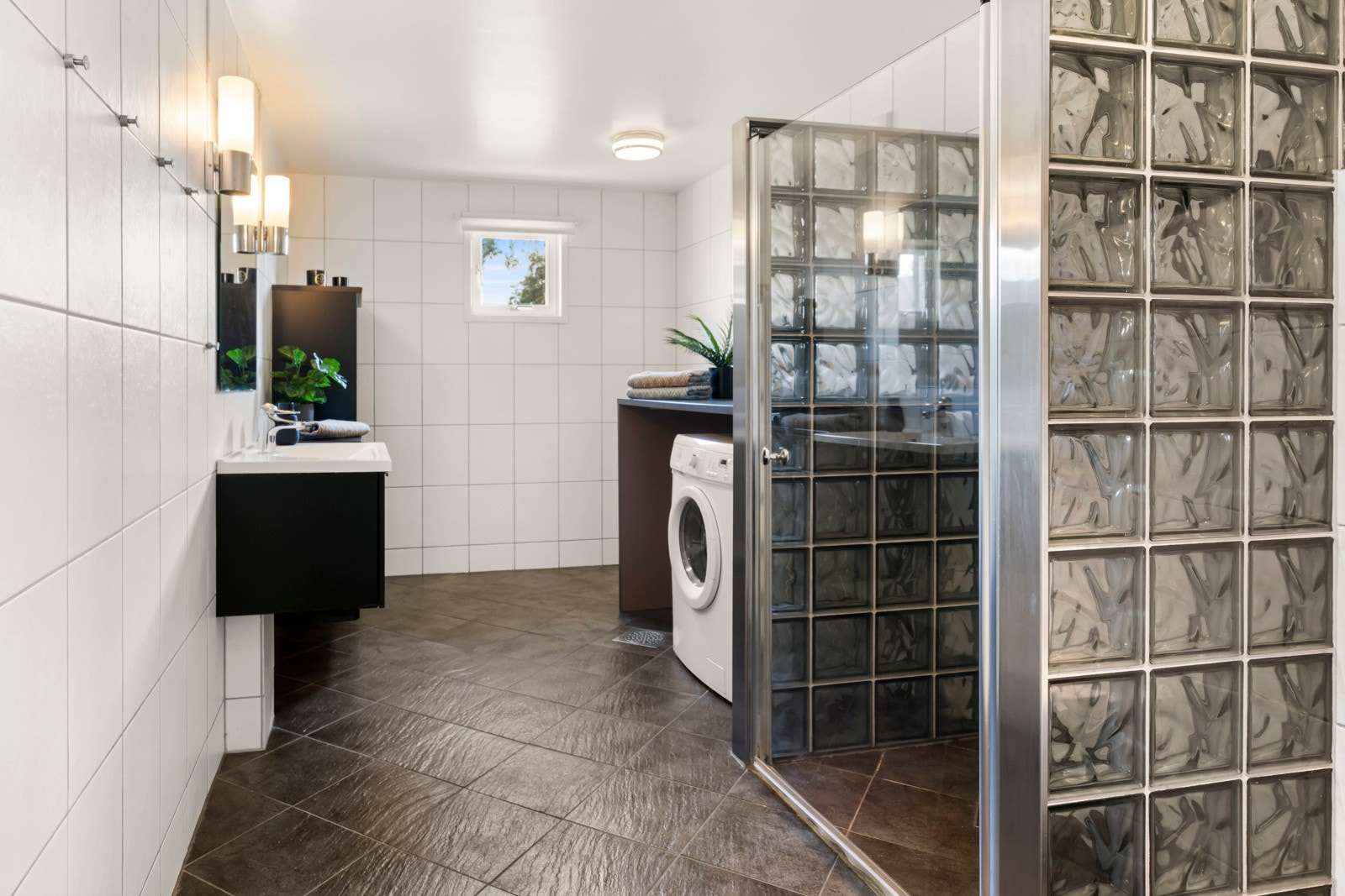 Flislagt baderom med lyse veggfliser og mørke gulvfliser, med varmekabler. Galleribilde