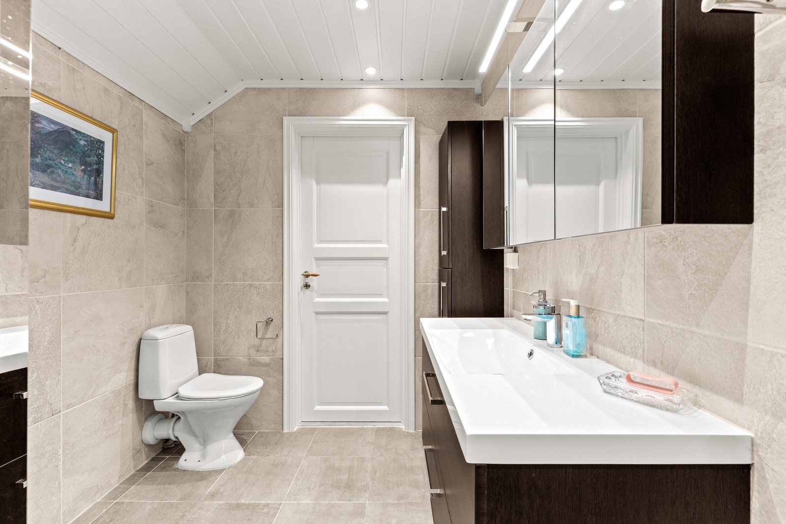 Det har flislagt gulv med elektrisk gulvvarme, flislagte vegger og malt panel i himling med downlights. Galleribilde