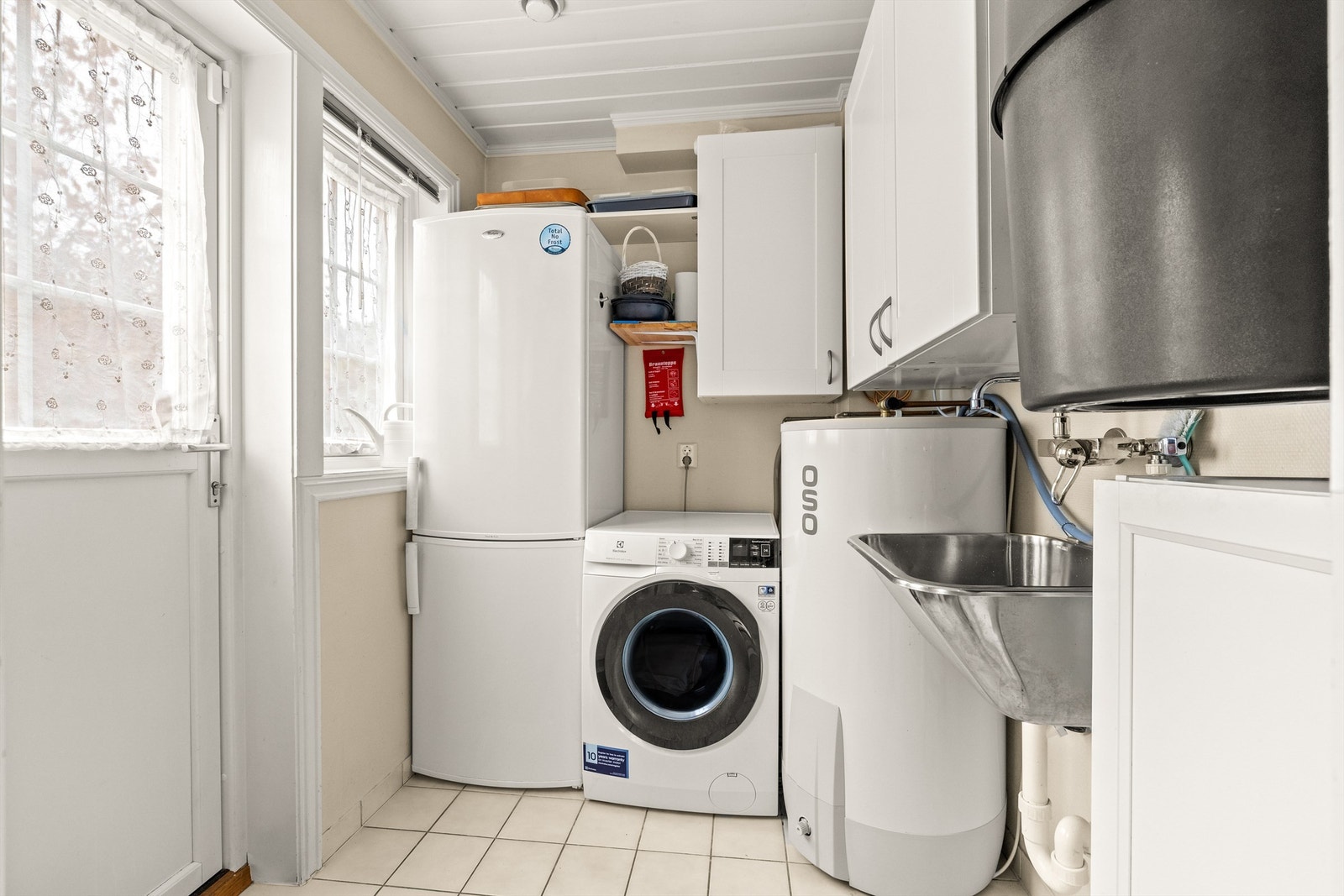 Vaskerommet er fra byggeår og er funksjonelt innredet med flislagt gulv, sokkelflis og vegger i malt strietapet. Egen inngang gjør rommet svært praktisk i hverdagen - perfekt for skitne klær, barnevogn, våte sko og lignende. Galleribilde