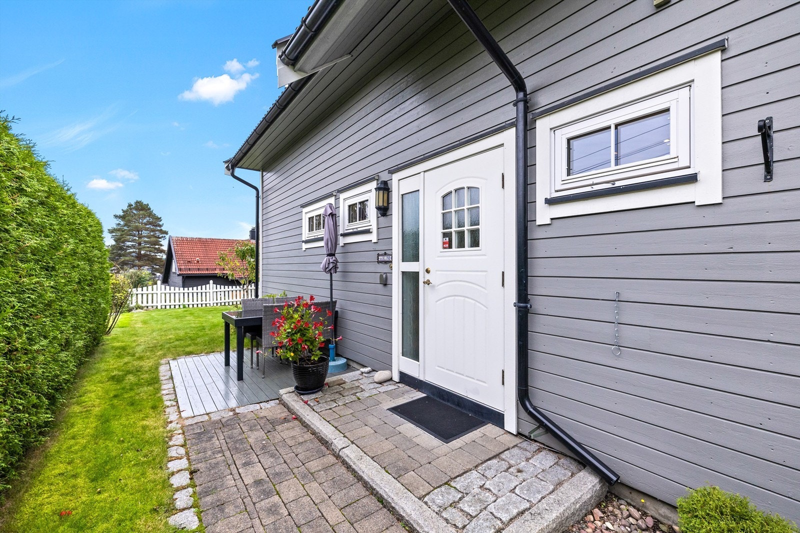 Inngangspartiet er pent opparbeidet med belegningsstein og trapp. Det er god plass til krukker og blomster som setter en hyggelig ramme rundt inngangen. Like ved finner du en liten, skjermet platting - perfekt for en sittegruppe eller en rolig kaffepause. Galleribilde