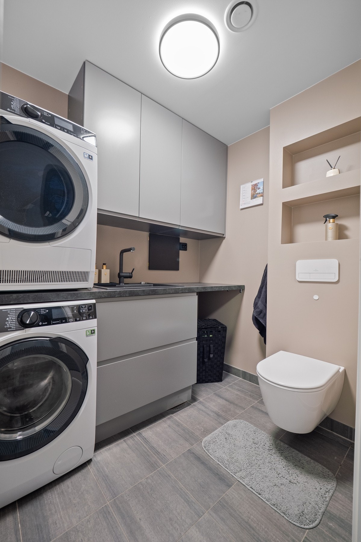 Rett innenfor entreen i første etasje er det et pent og praktisk vaskerom som ble pusset opp i 2022. Vaskerommet har grå fliser på gulv med gulvvarme. Galleribilde