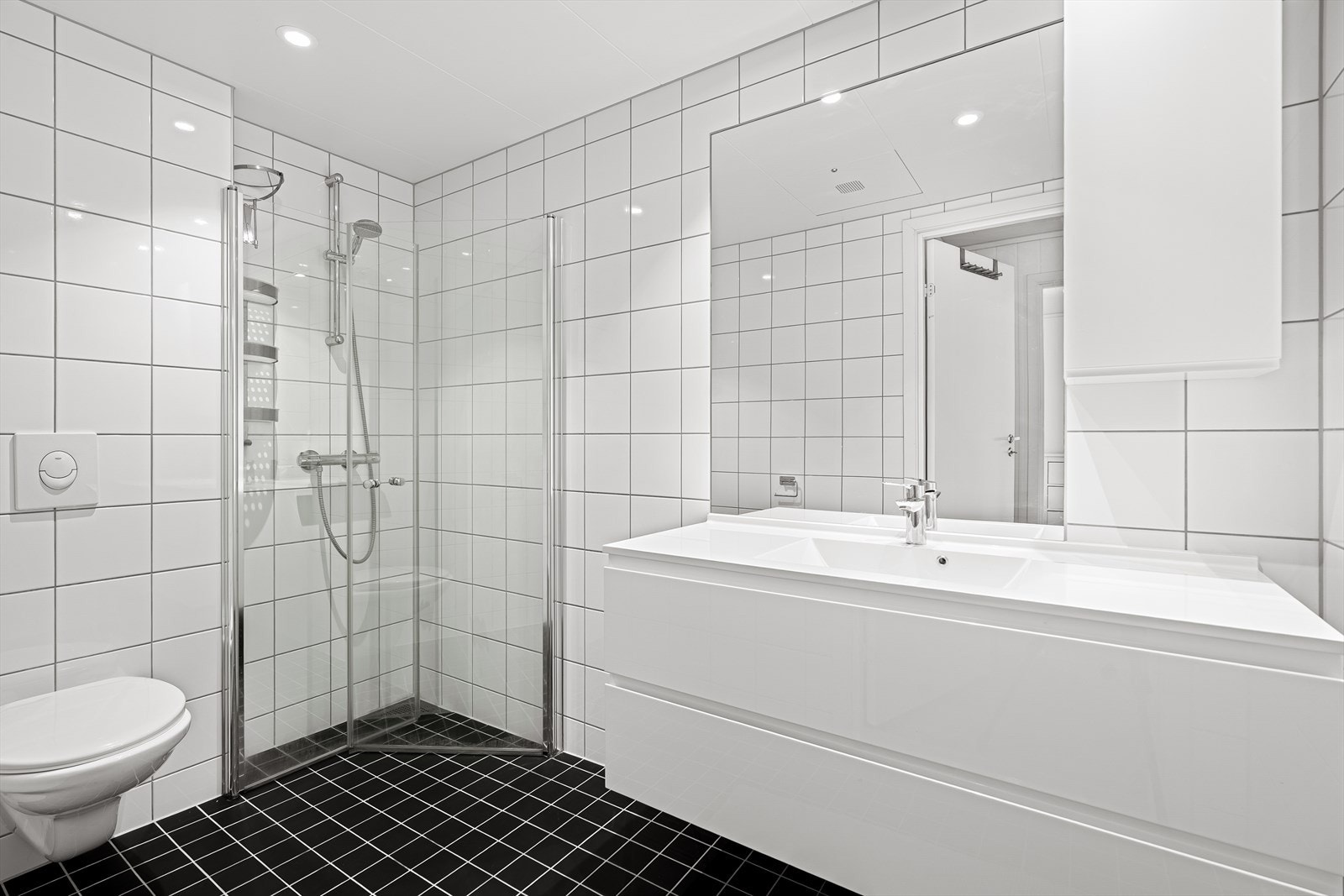 - Bad av god størrelse med dusjhjørne med innfellbare glassdører, vegghengt WC og romslig servant med skuffer - Galleribilde