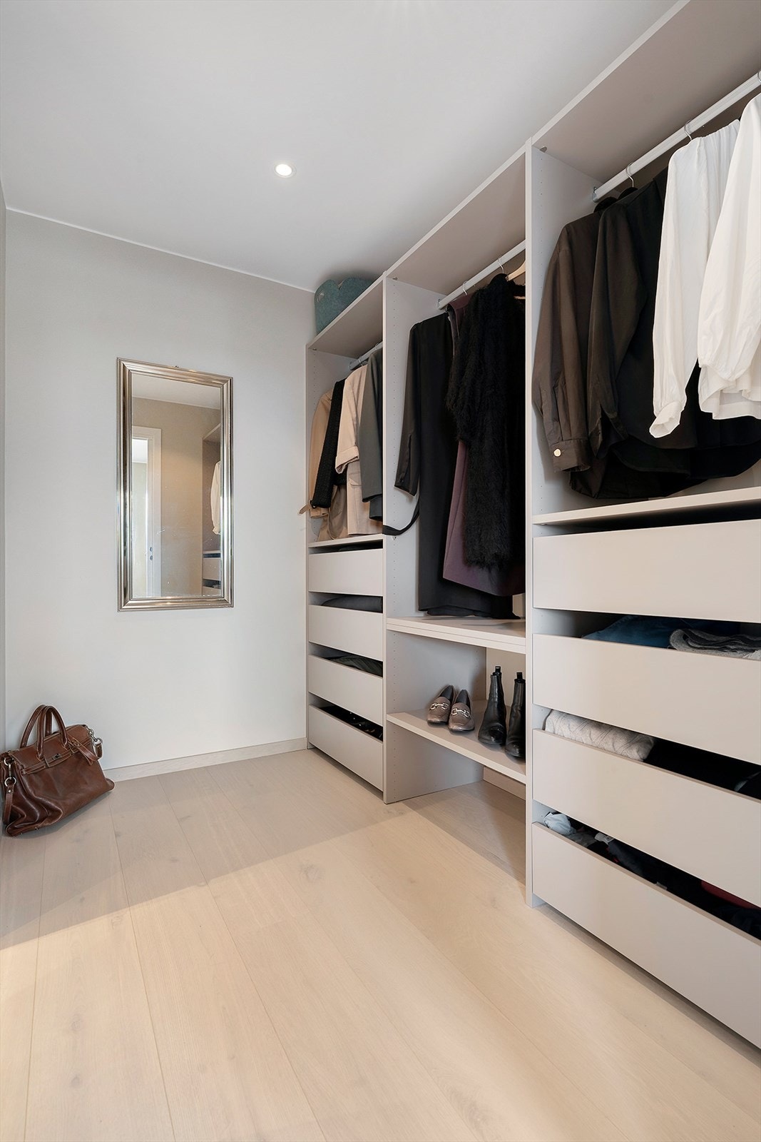 Mellom tv-stua og det ene bade,t er det eget walk-in closet med skuffer, hyller og oppheng for klær Galleribilde