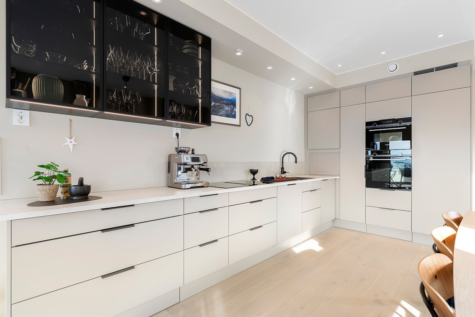 Moderne kjøkken med innredning fra JKE. Praktiske løsninger med blant annet rom for kjøkkenmaskin/ kaffetrakter i enden av benken. Galleribilde