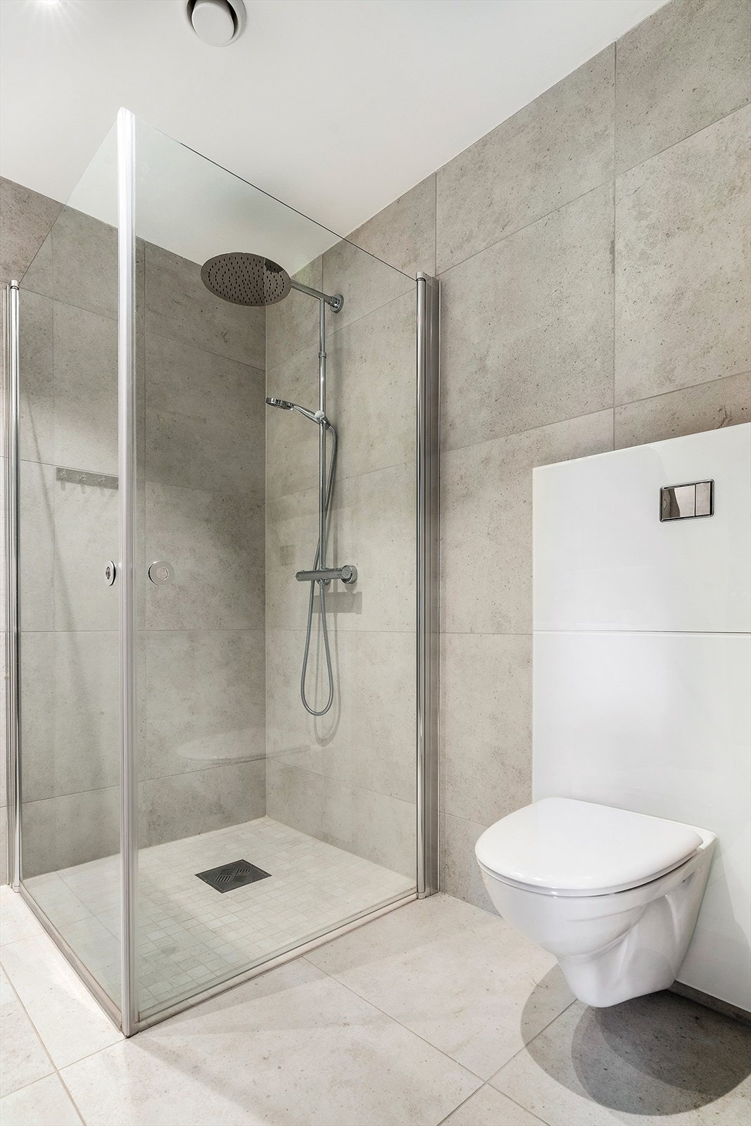 Det ene av to bad ligger innefor garderoberommet. Stilrent med 60 x 60 flis på gulv og vegg Galleribilde