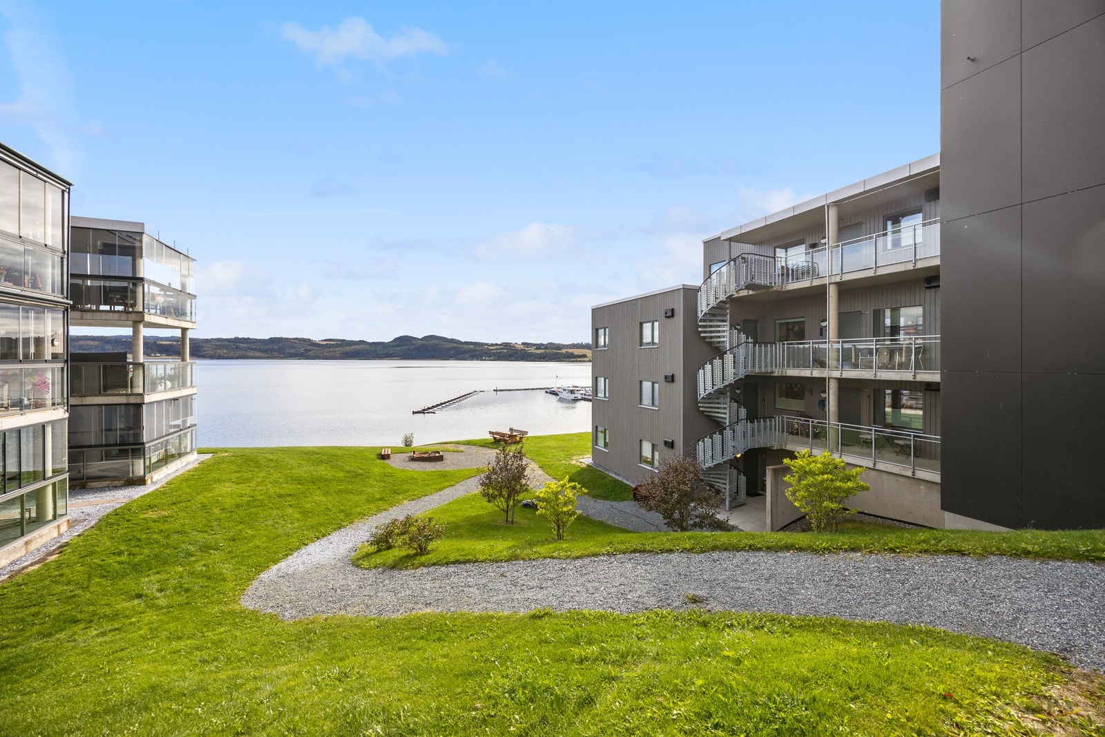 Pent opparbeidet fellesareal med trær, benker og gruslagte stier Galleribilde