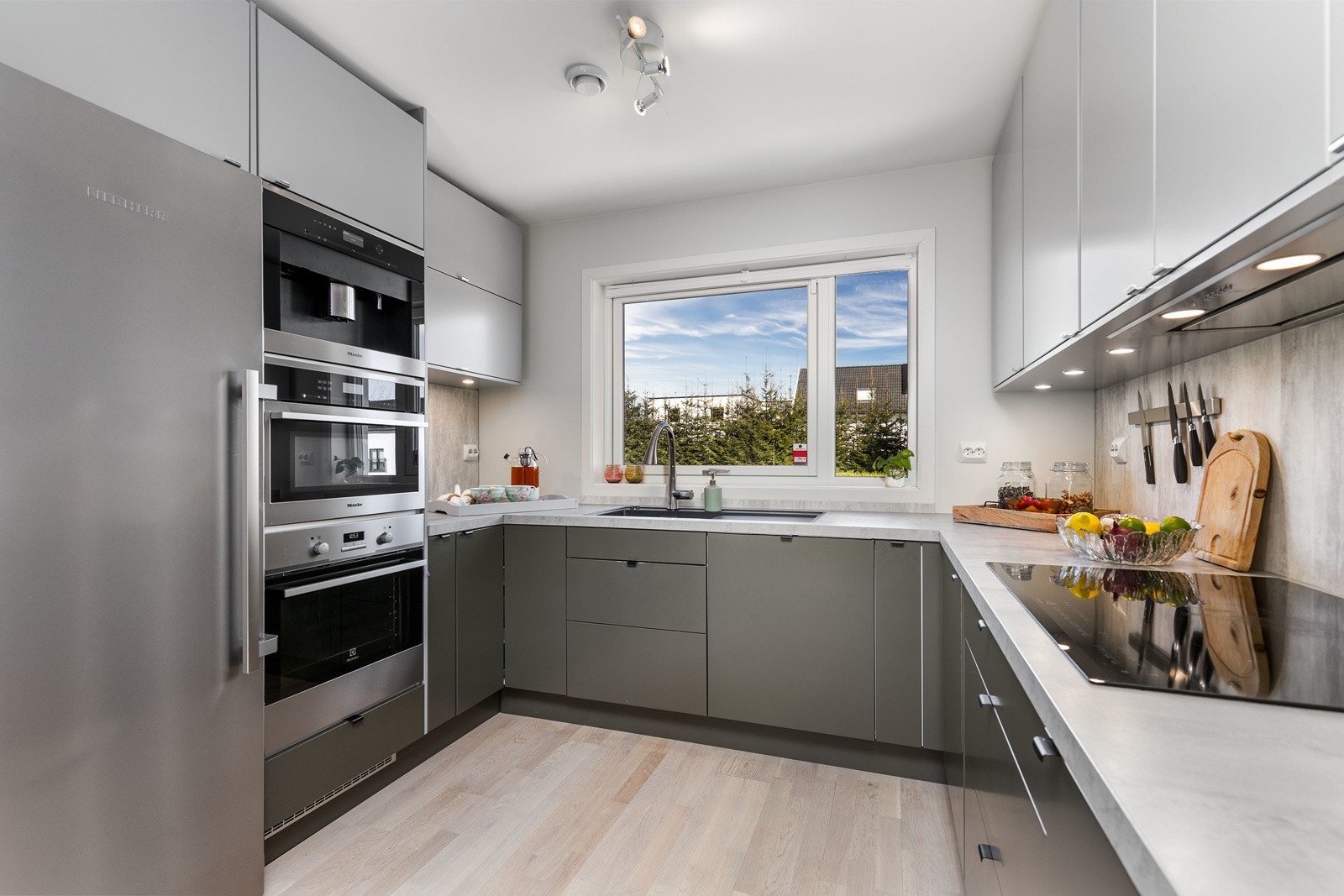 Kjøkkenet har svært mye oppbevaringsplass som følge av gode hjørneløsninger. Kjøkkenet har overskap i lysegrå utførelse, samt underskap i dempet mosegrønn utførelse - kombinasjonen skaper en harmonisk kontrast i rommet. Galleribilde