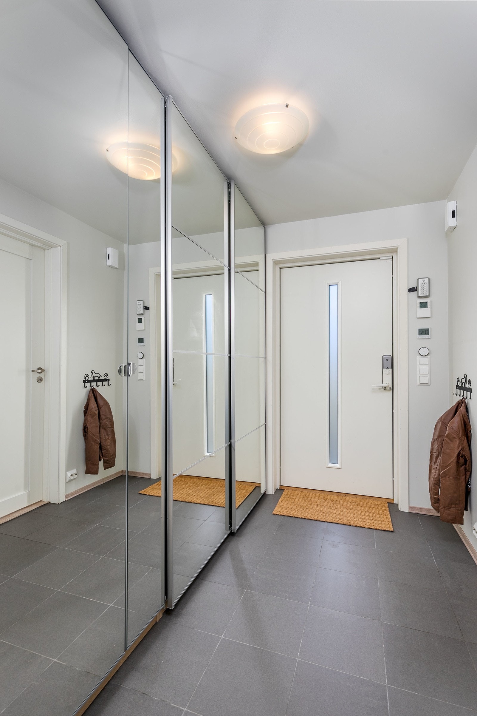 Flott entré med flislagt gulv og lysmalte slette veggflater. Stor skyvedørsgarderobe med speil sørger for rikelig med oppbevaringsplass for klær og sko. Galleribilde