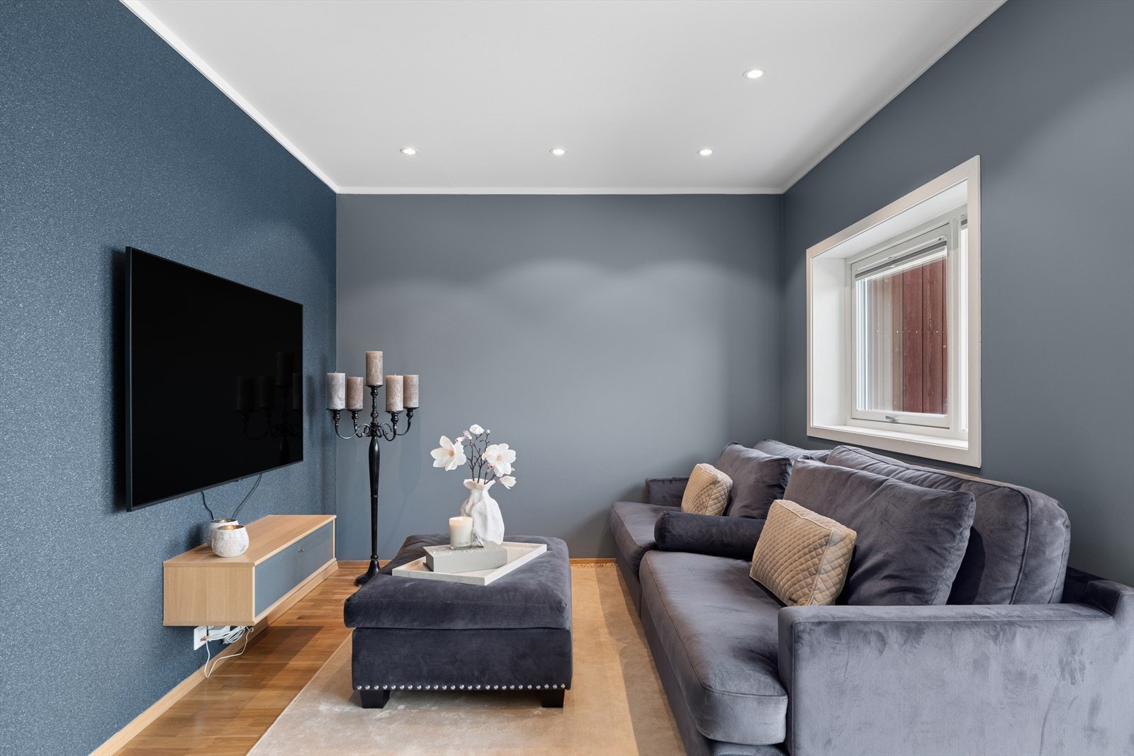 Stuen har downlights elegant integrert i himlingen, som gir et moderne uttrykk og behagelig belysning. Dette skaper en lun og stilren atmosfære, samtidig som det fremhever rommets kvaliteter på en diskret og effektiv måte. Galleribilde