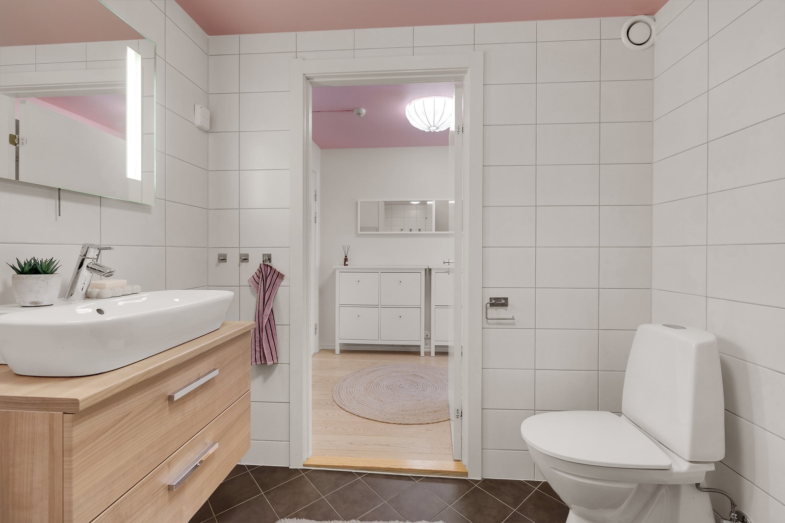 Baderomsinnredning bestående av servantskap med ovenpåliggende servant, vegghengt speil og toalett. Galleribilde