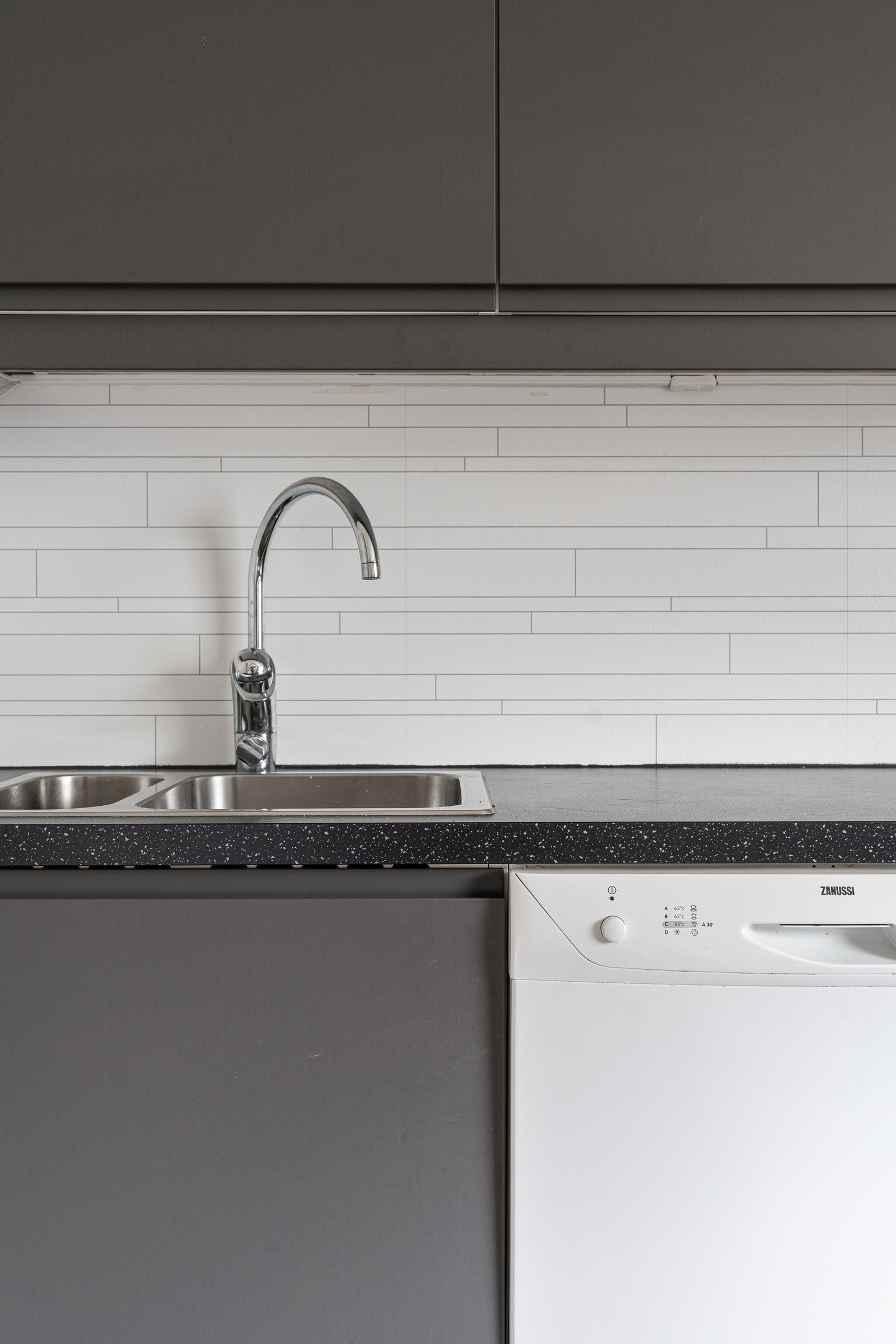 Pent kjøkken fra ca. 2021 med slette fronter og laminat benkeplate, samt kitchenboard over benk.