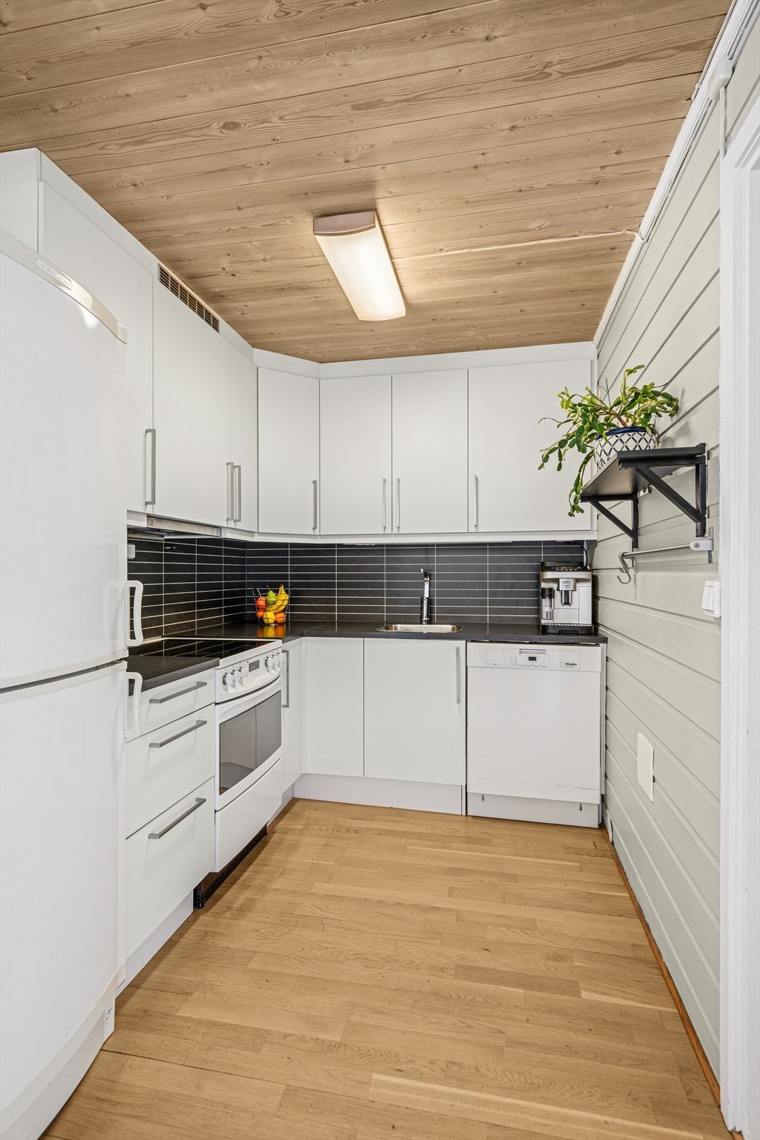 Lyst og tidløst kjøkken med alt en måtte trenge av skap-, skuff- og benkeplass. Galleribilde