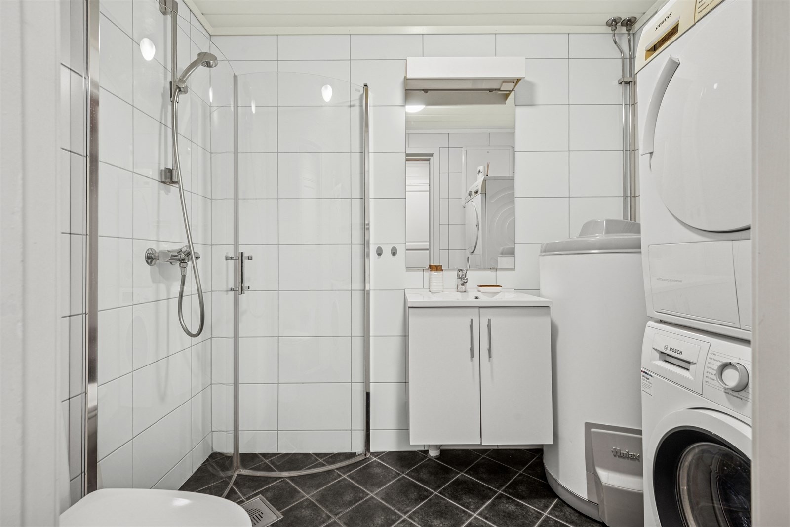 Badet er utstyrt med dusjhjørne, vegghengt wc, opplegg for vaskemaskin/tørketrommel samt lys baderomsinnredning. Galleribilde