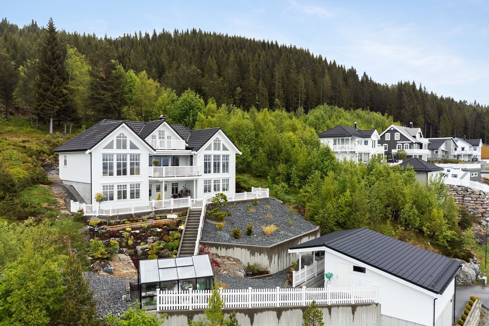 Boligen ligger høyt og fint til og tomta er opparbeidet med skråninger med beplantning Galleribilde