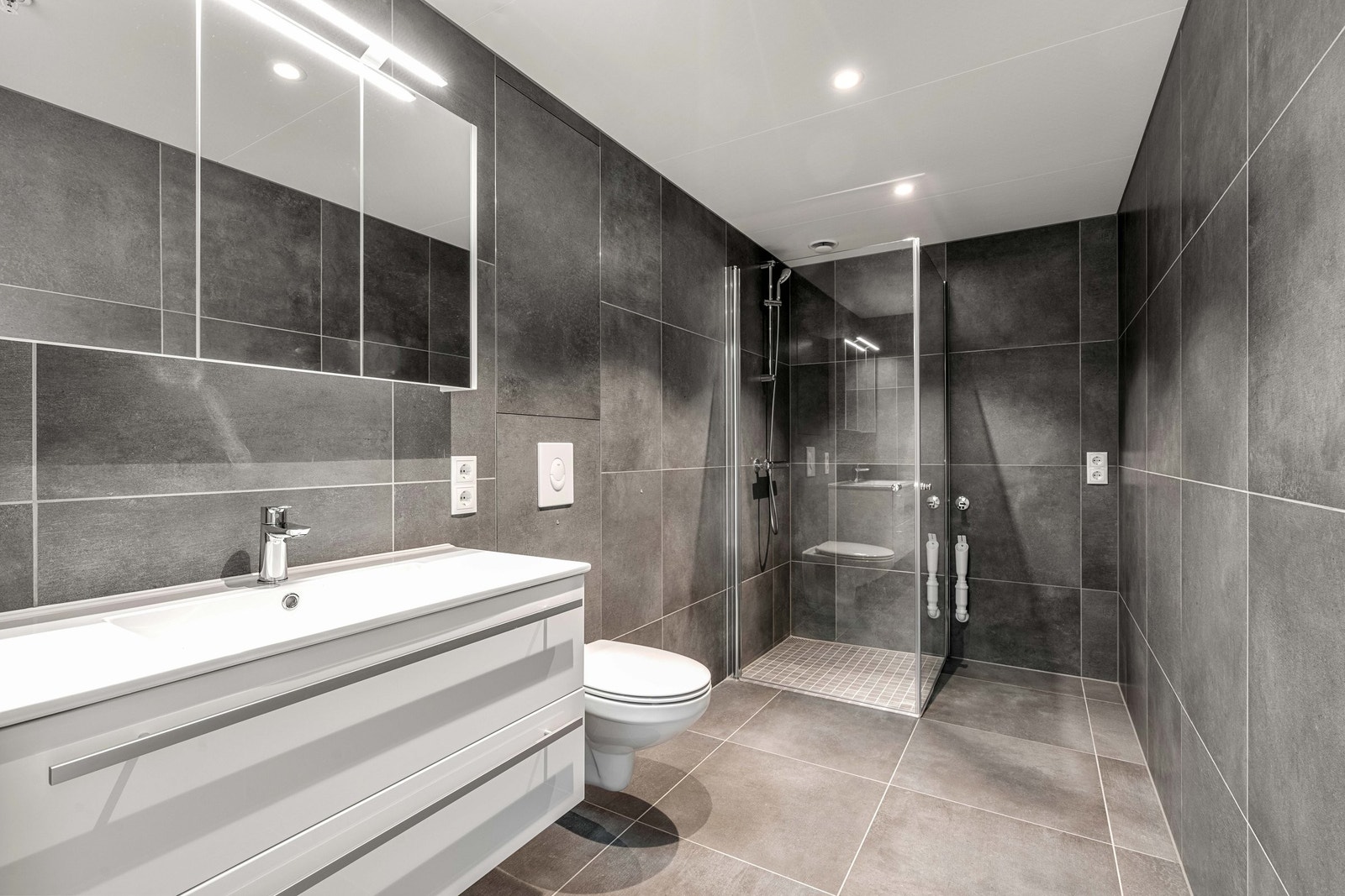 Bad med store fliser på gulv og vegger. Galleribilde