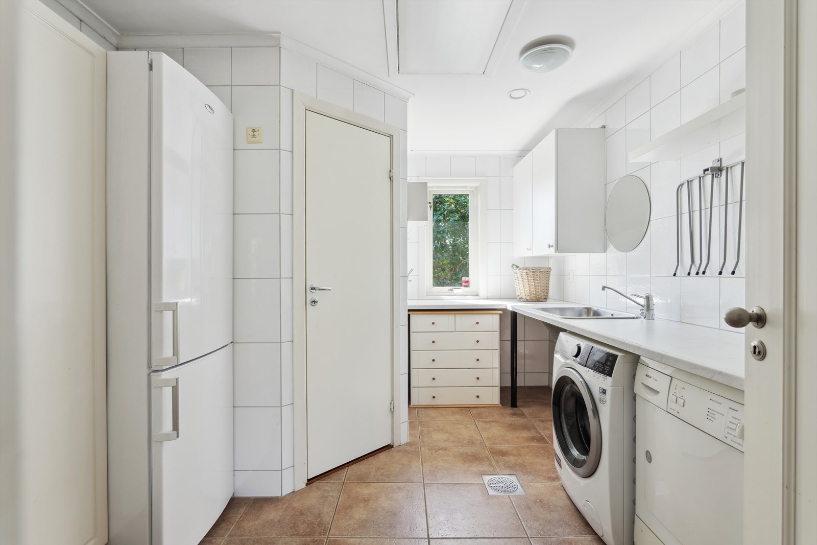 Praktisk vaskerom med opplegg for vaskemaskin og utslagsvask og med inngang til teknisk rom Galleribilde