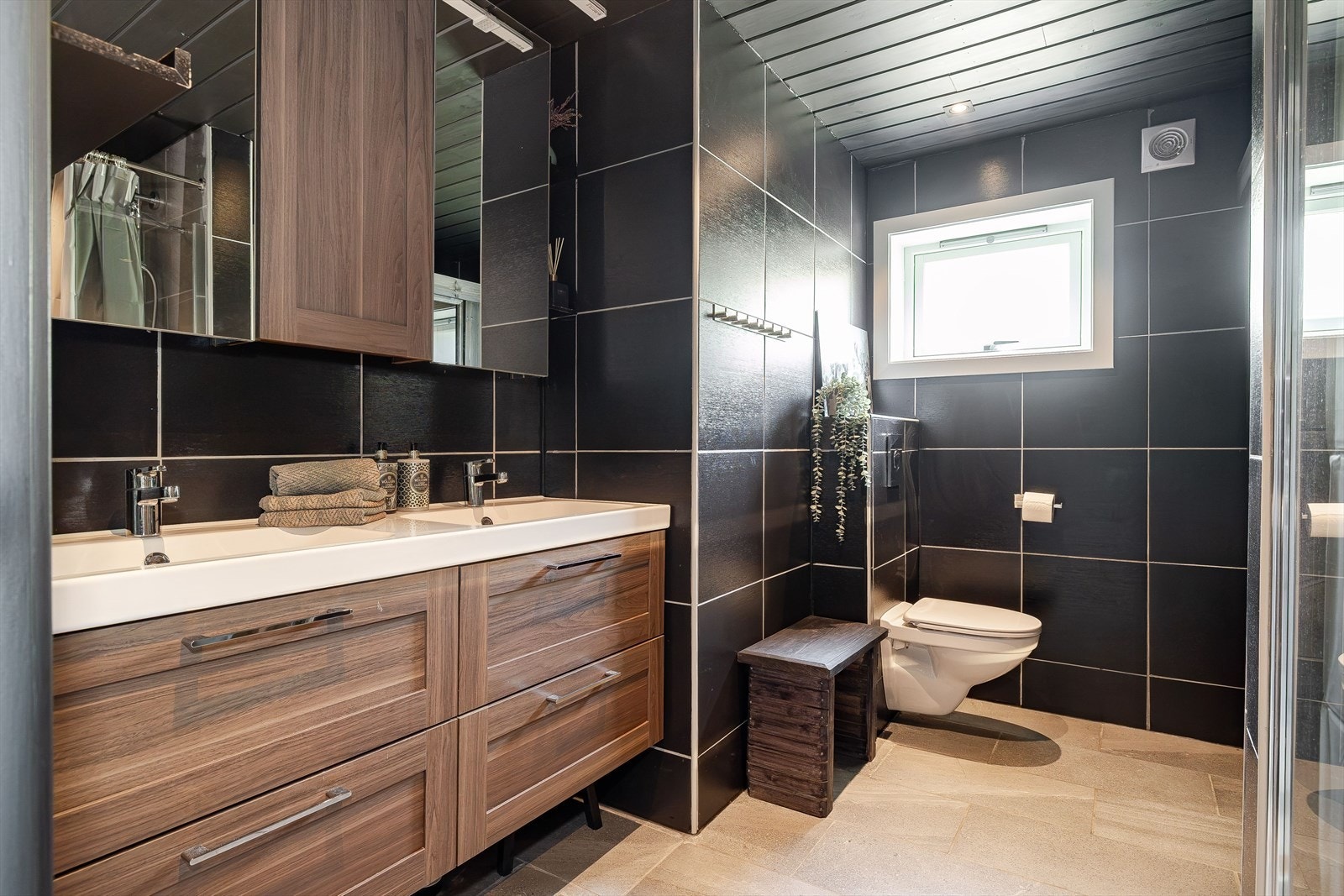 Lekkert og pent bad med dobbelservant på innredning, vegghengt toalett og dusjkabinett. Galleribilde