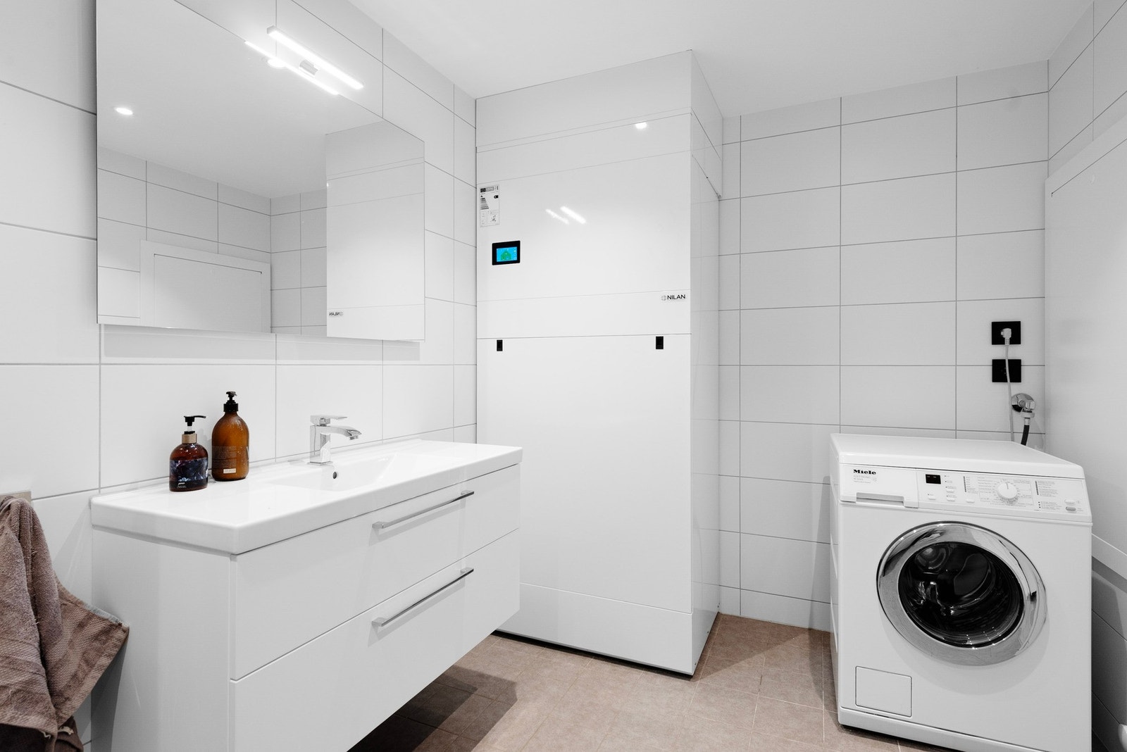 Her har du god oppbevaringsplass i servantinnredning med skuffer og opplegg til både vaskemaskin og tørketrommel Galleribilde